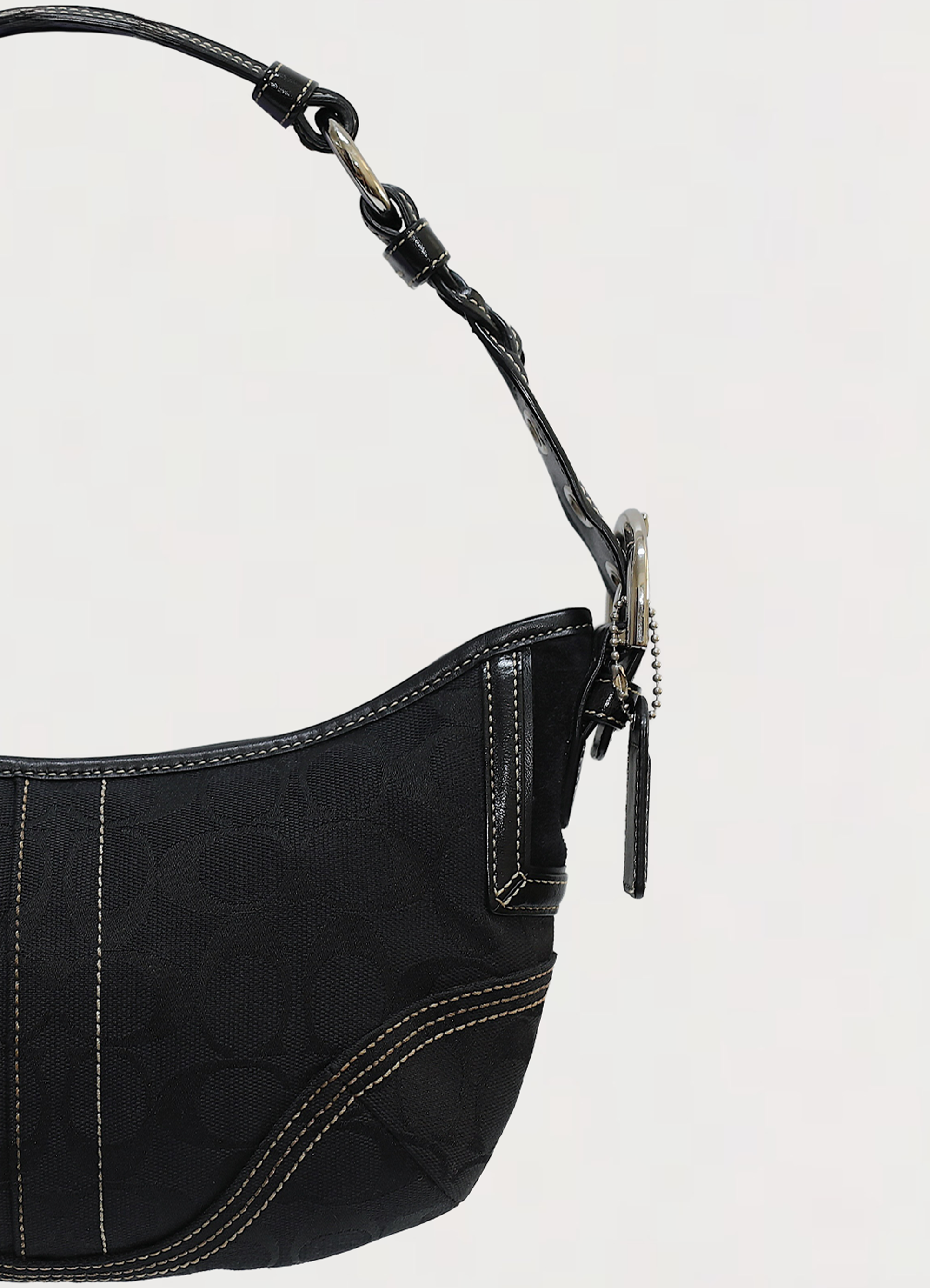 Vintage Coach Soho hobo bag in black signature canvas with leather trim showing close up of left side