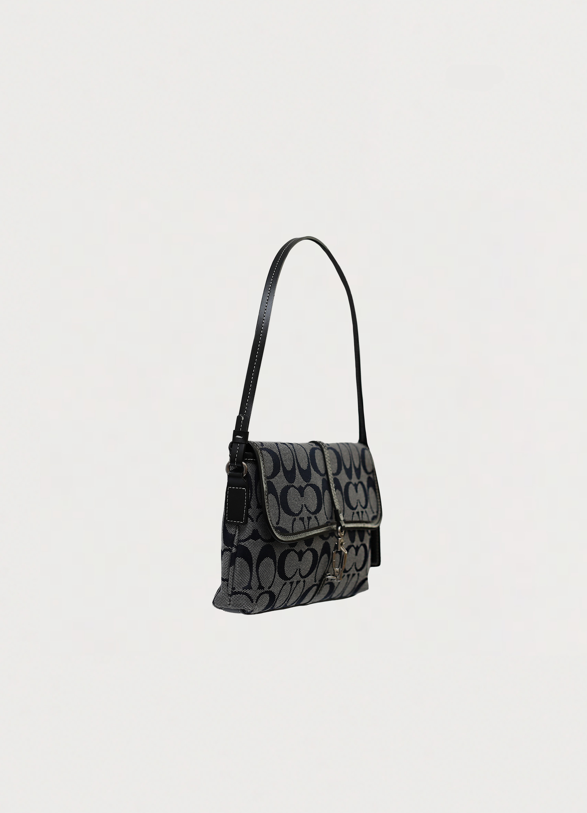 Angled side view of Coach demi flap bag showing slim baguette silhouette