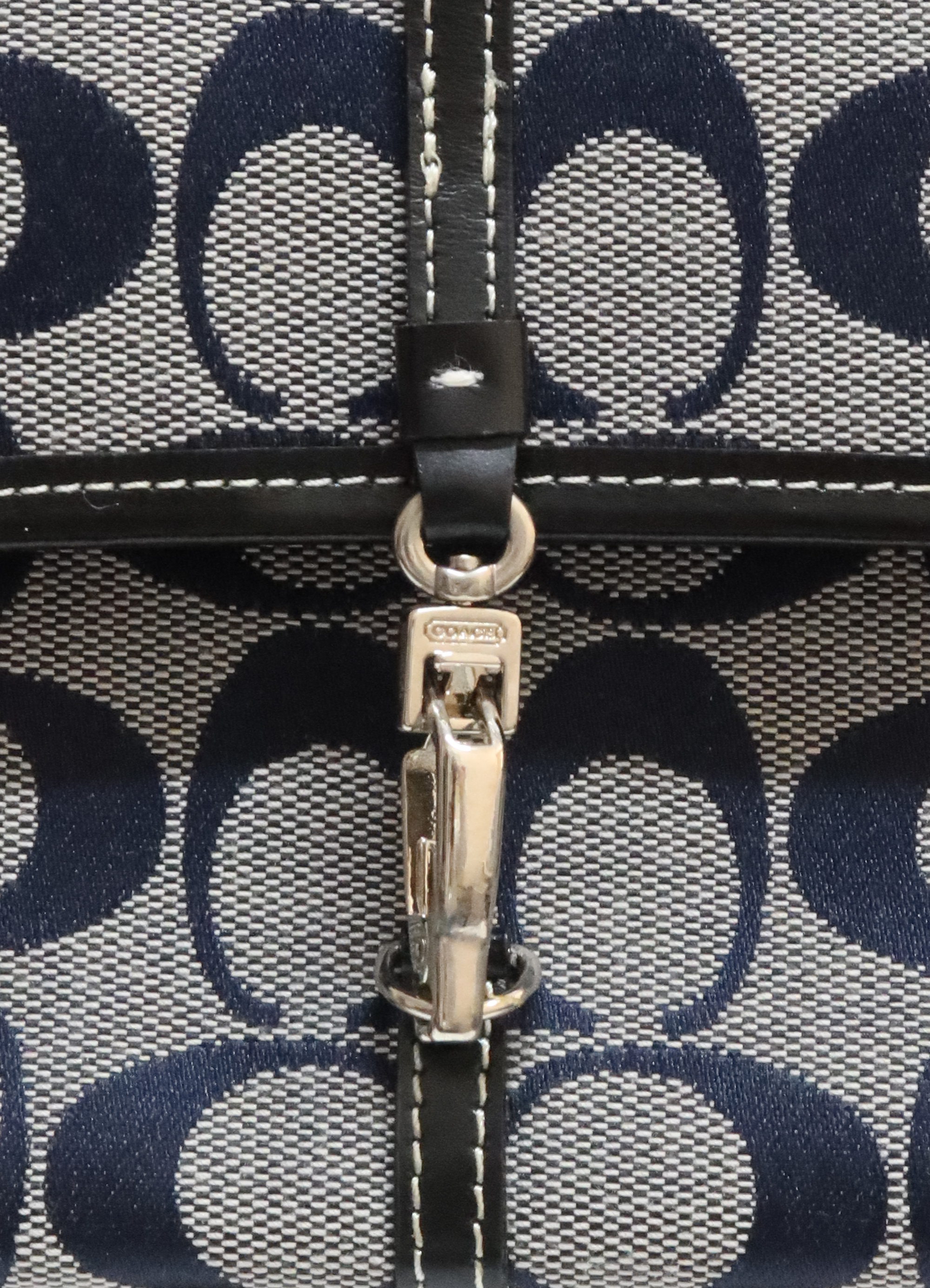 Close up of the silver-tone metal lobster clip closure on the front of the Coach bag