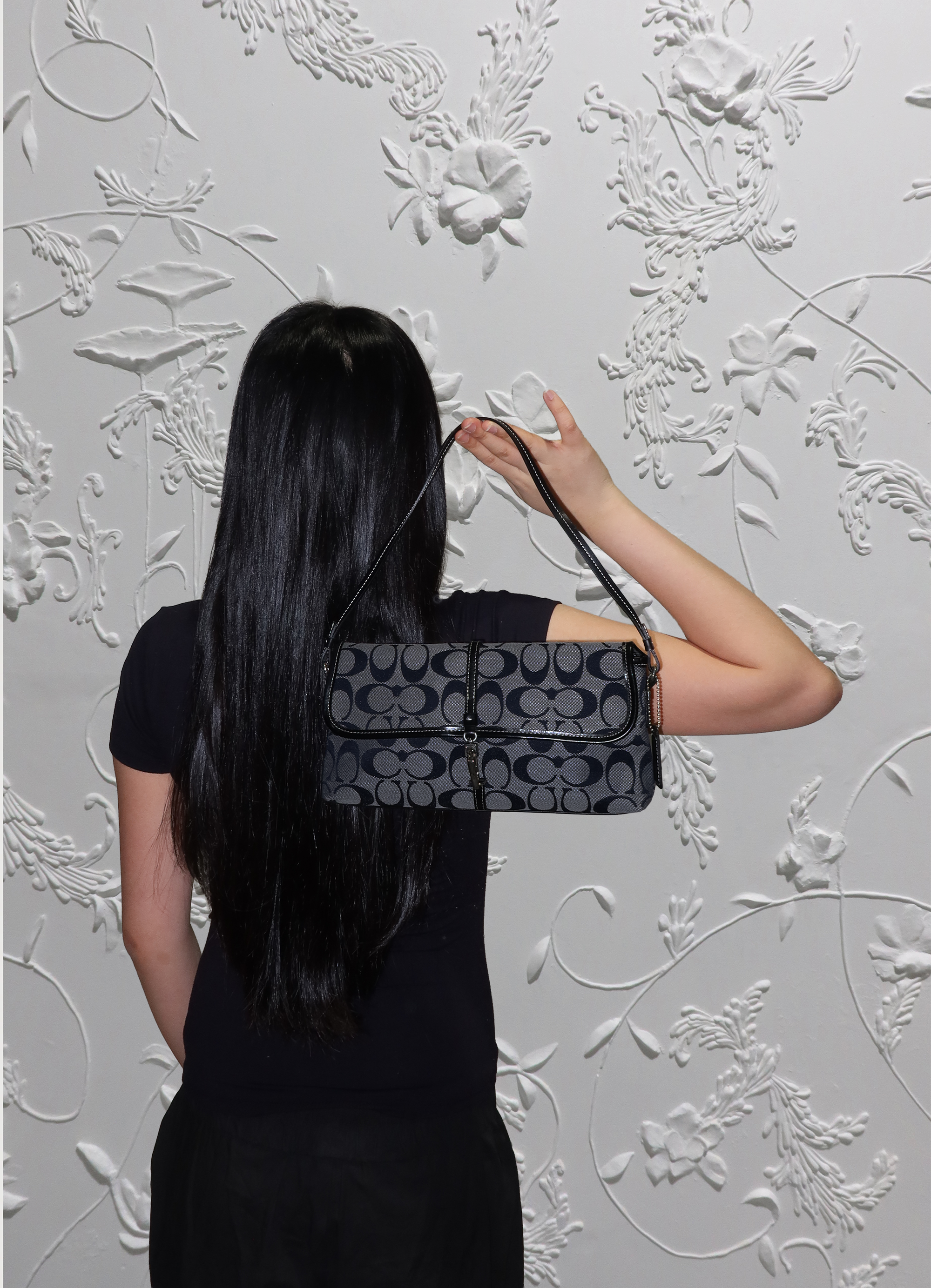 Black Coach signature demi flap bag held by model