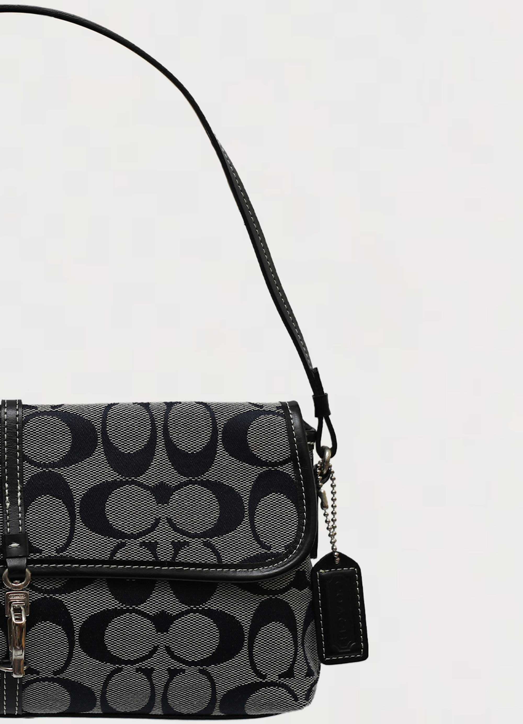 Close up of the slim black leather shoulder strap and hardware on the Coach demi bag