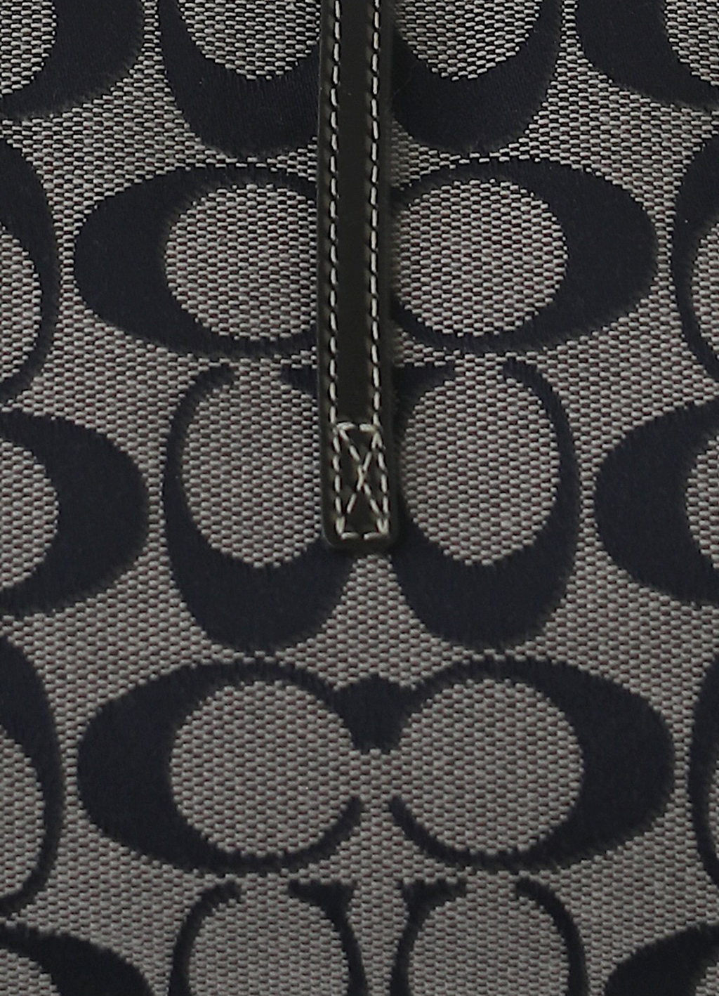 Macro shot of authentic black and grey Coach signature "C" jacquard canvas