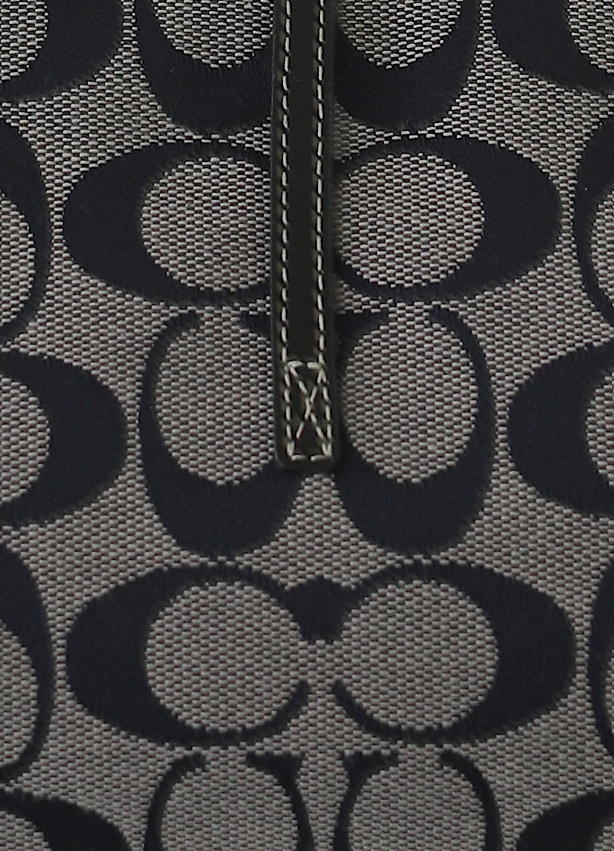 Macro shot of authentic black and grey Coach signature "C" jacquard canvas