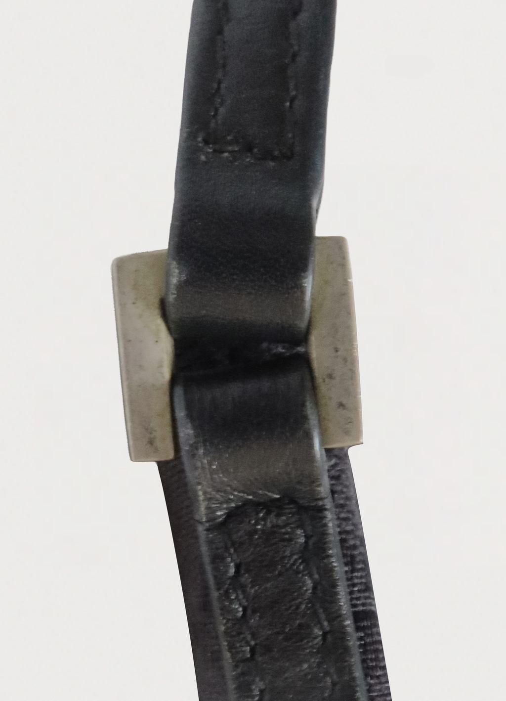 Detail shot of the black leather shoulder strap and square silver-tone hardware