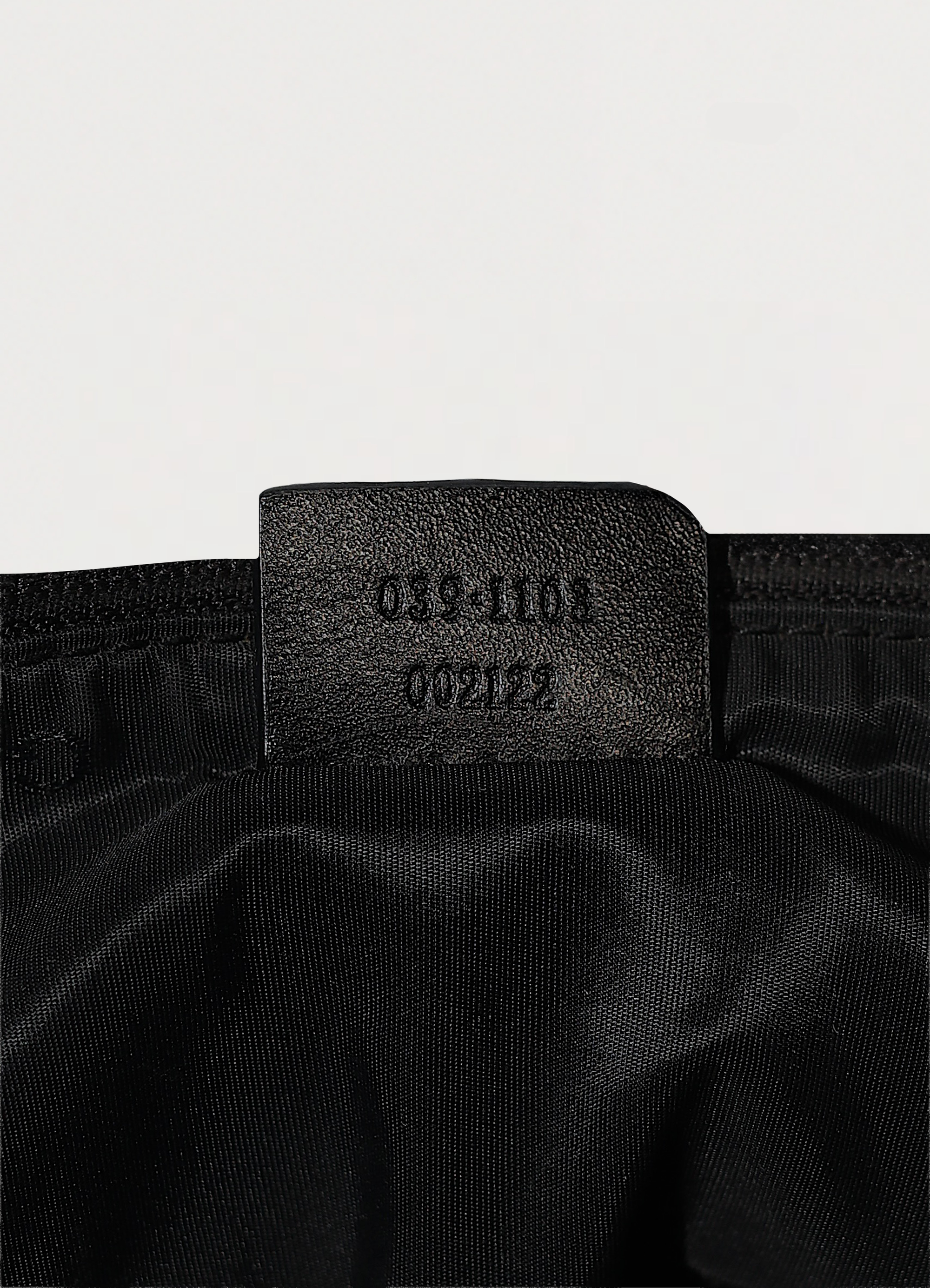 GG monogram boat back in black signature canvas with leather trim showing close up of label tag of serial number