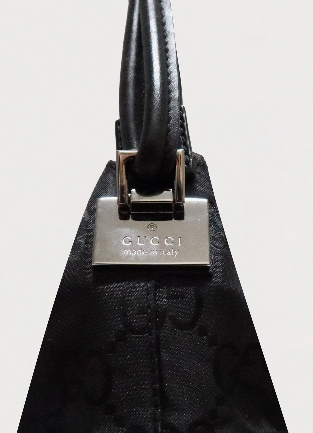 Close up of silver-tone engraved Gucci clasp hardware on black canvas