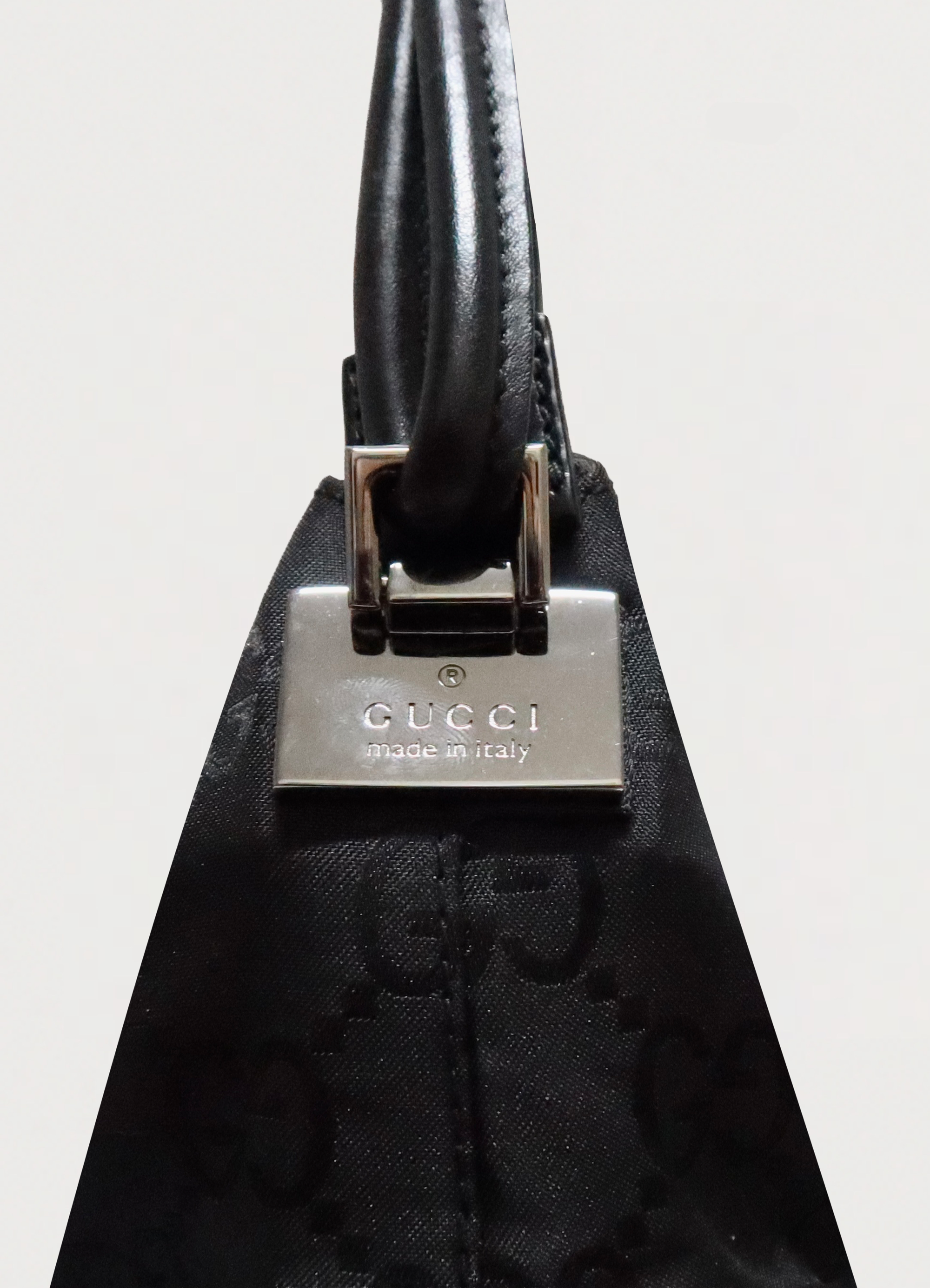 Close up of silver-tone engraved Gucci clasp hardware on black canvas
