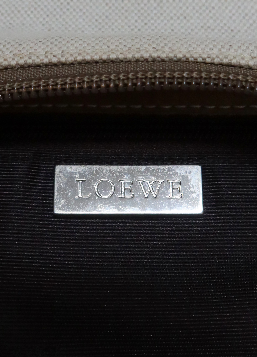 Close up of silver-tone Loewe logo plaque inside the pochette