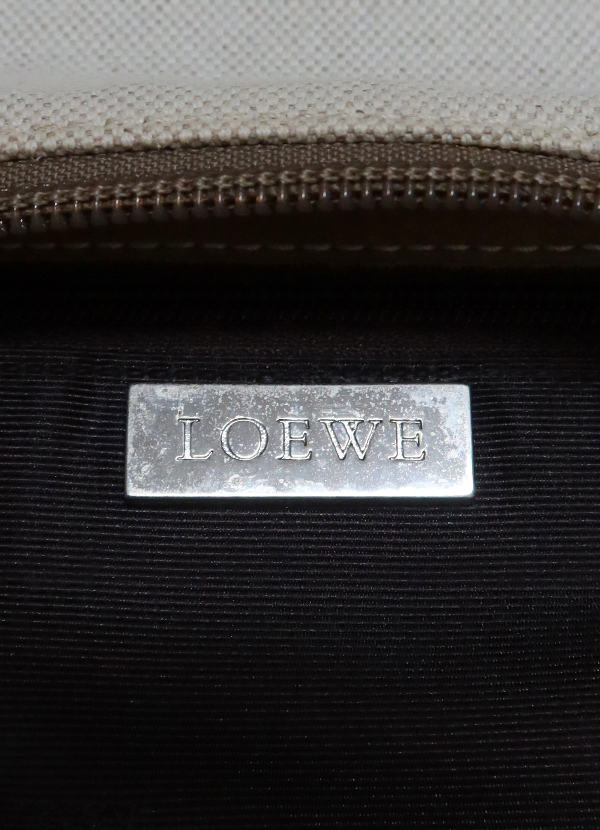 Close up of silver-tone Loewe logo plaque inside the pochette
