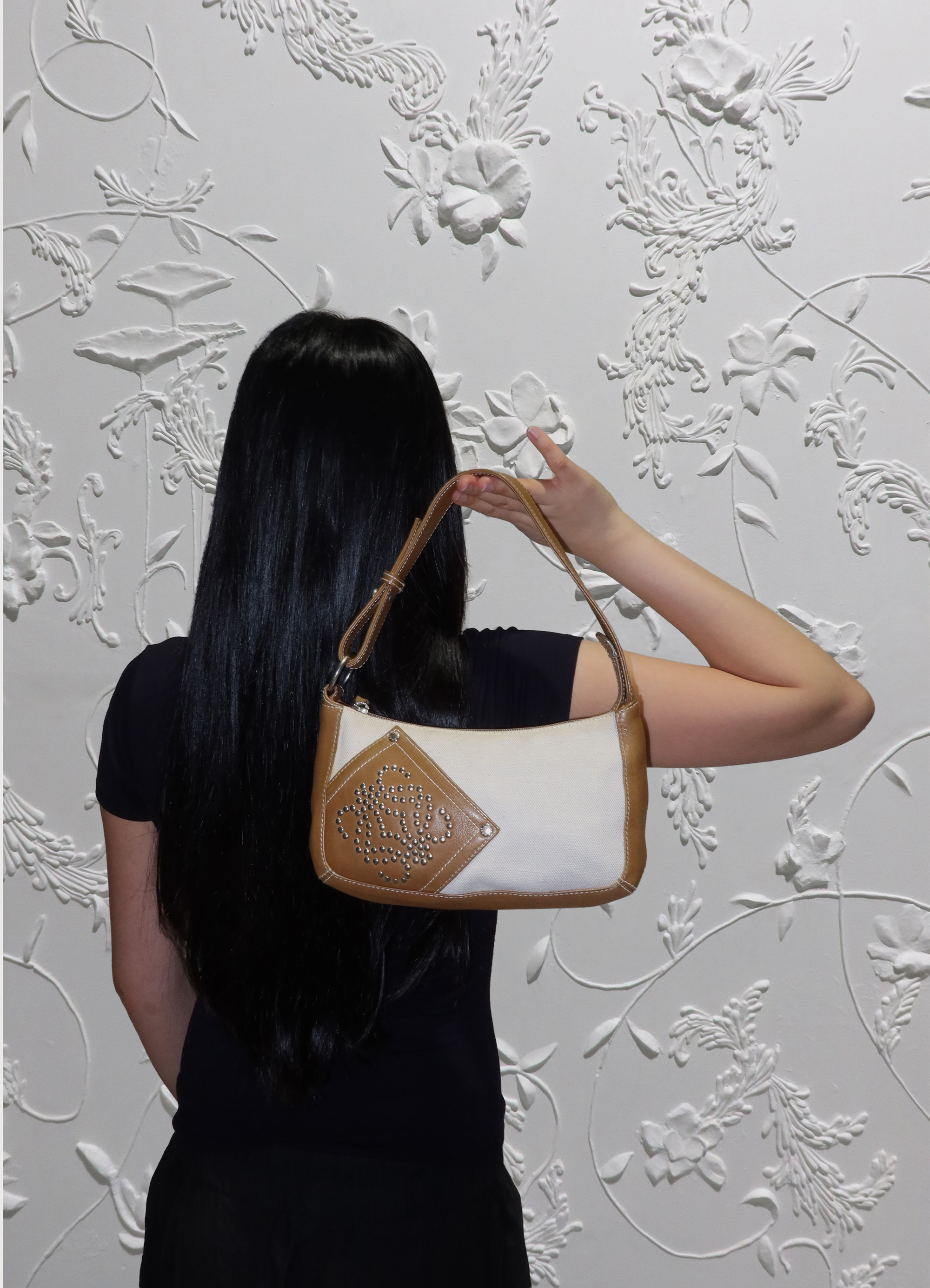 Cream Loewe Anagram pochette bag held by model
