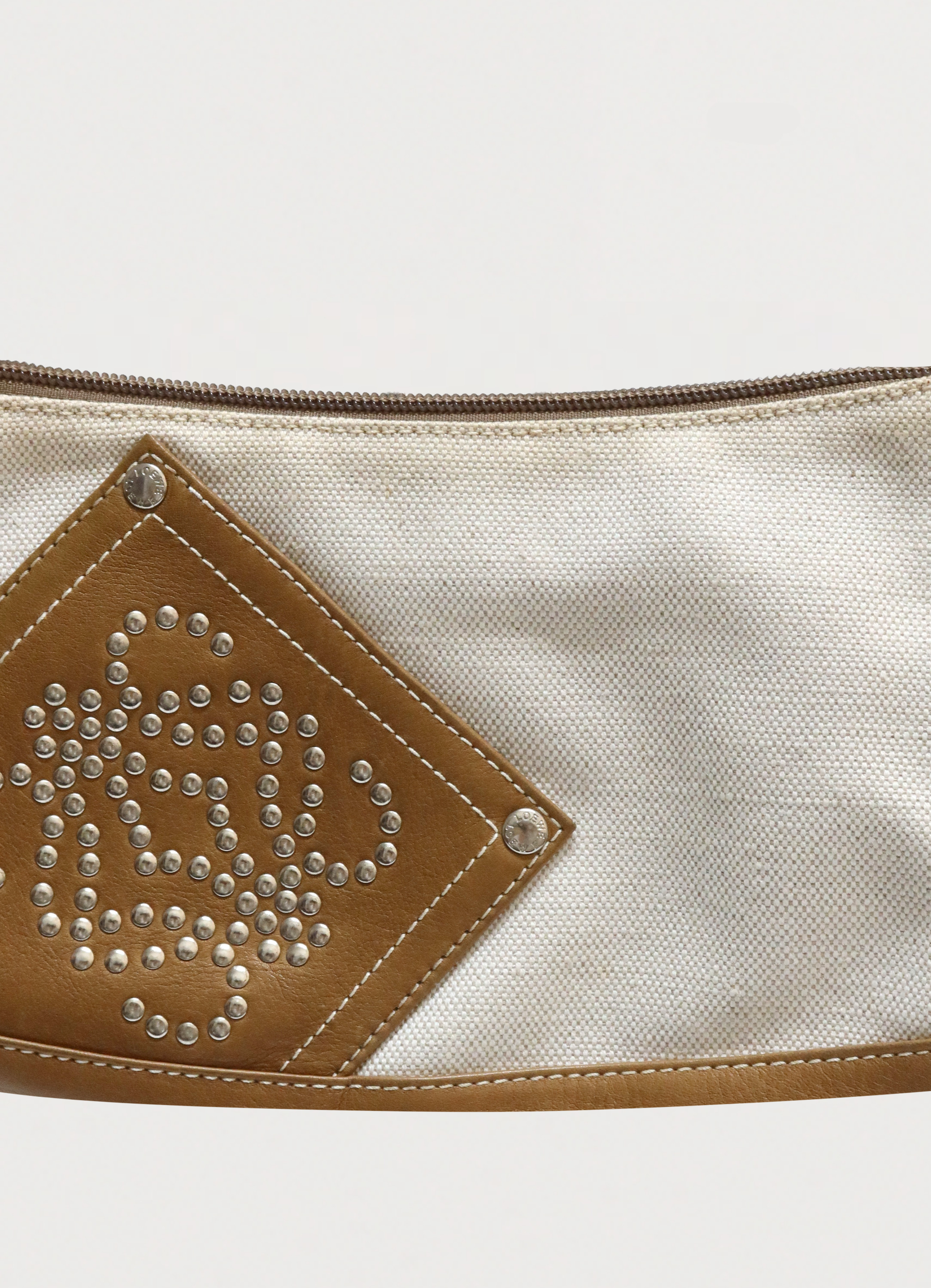Macro detail of the studded Loewe Anagram logo on the leather corner patch