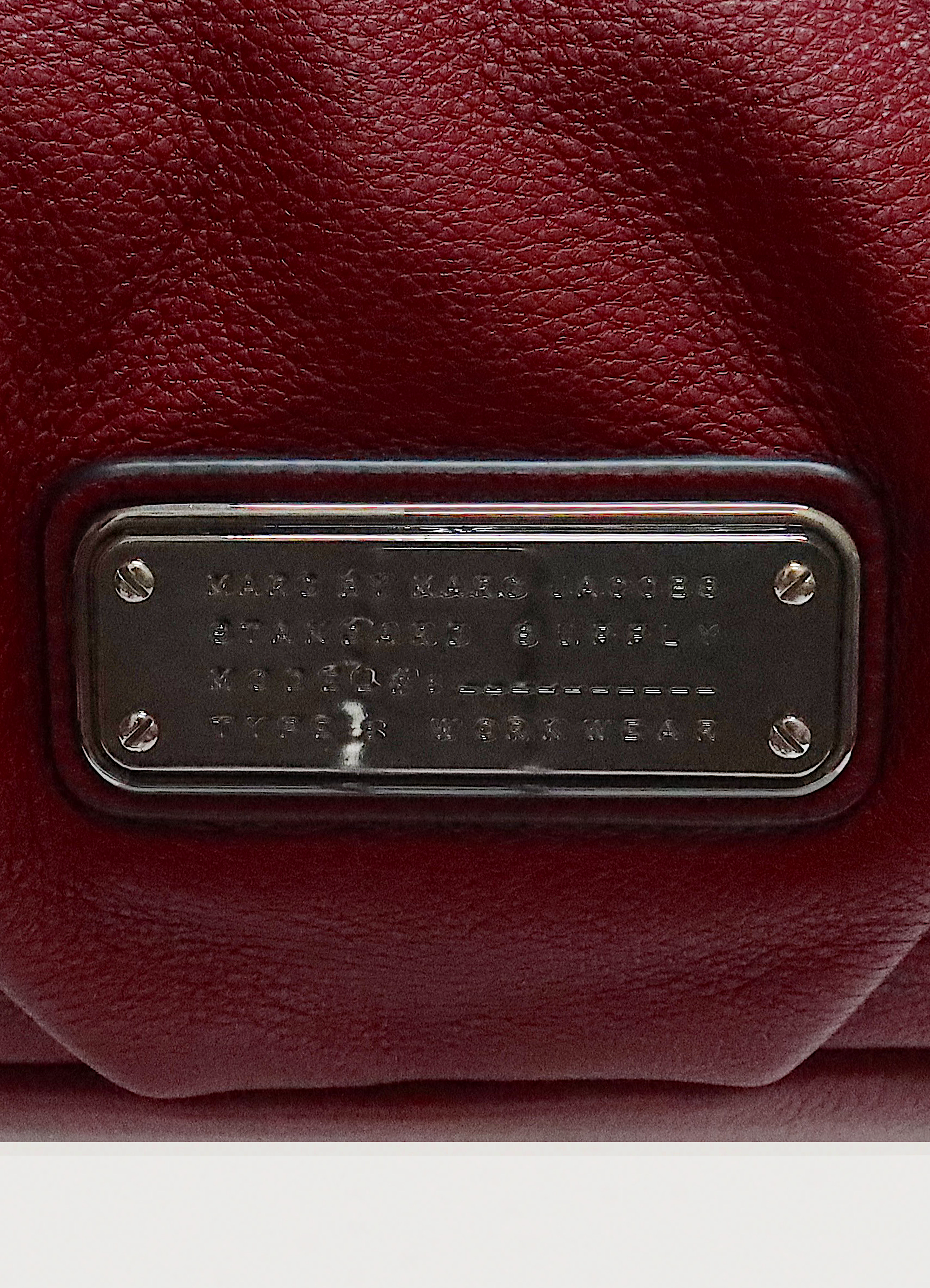 Close up of silver-tone Marc by Marc Jacobs Standard Supply logo plaque