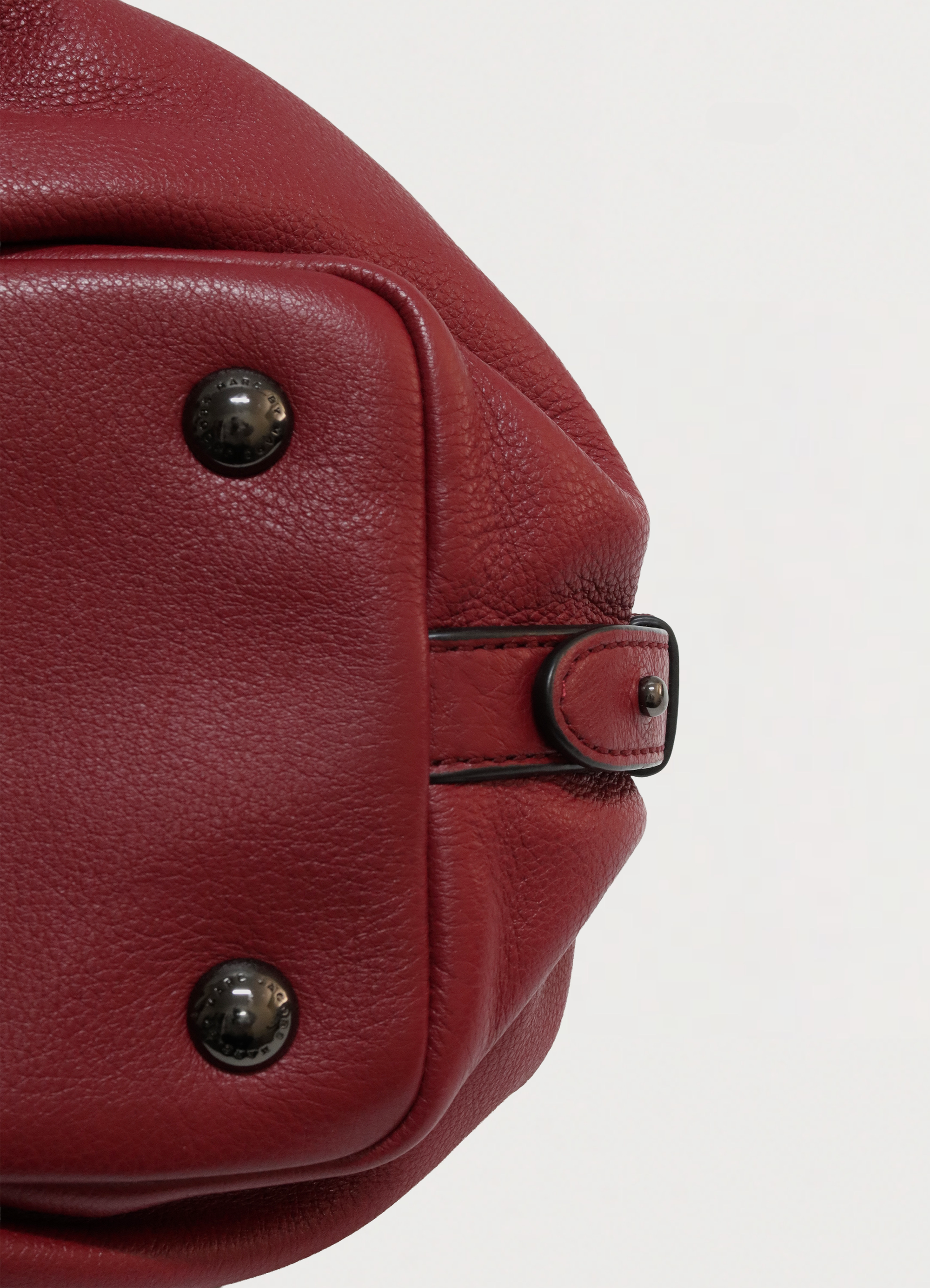 Close up of bottom corner and leather texture on Marc Jacobs satchel showing bag studs