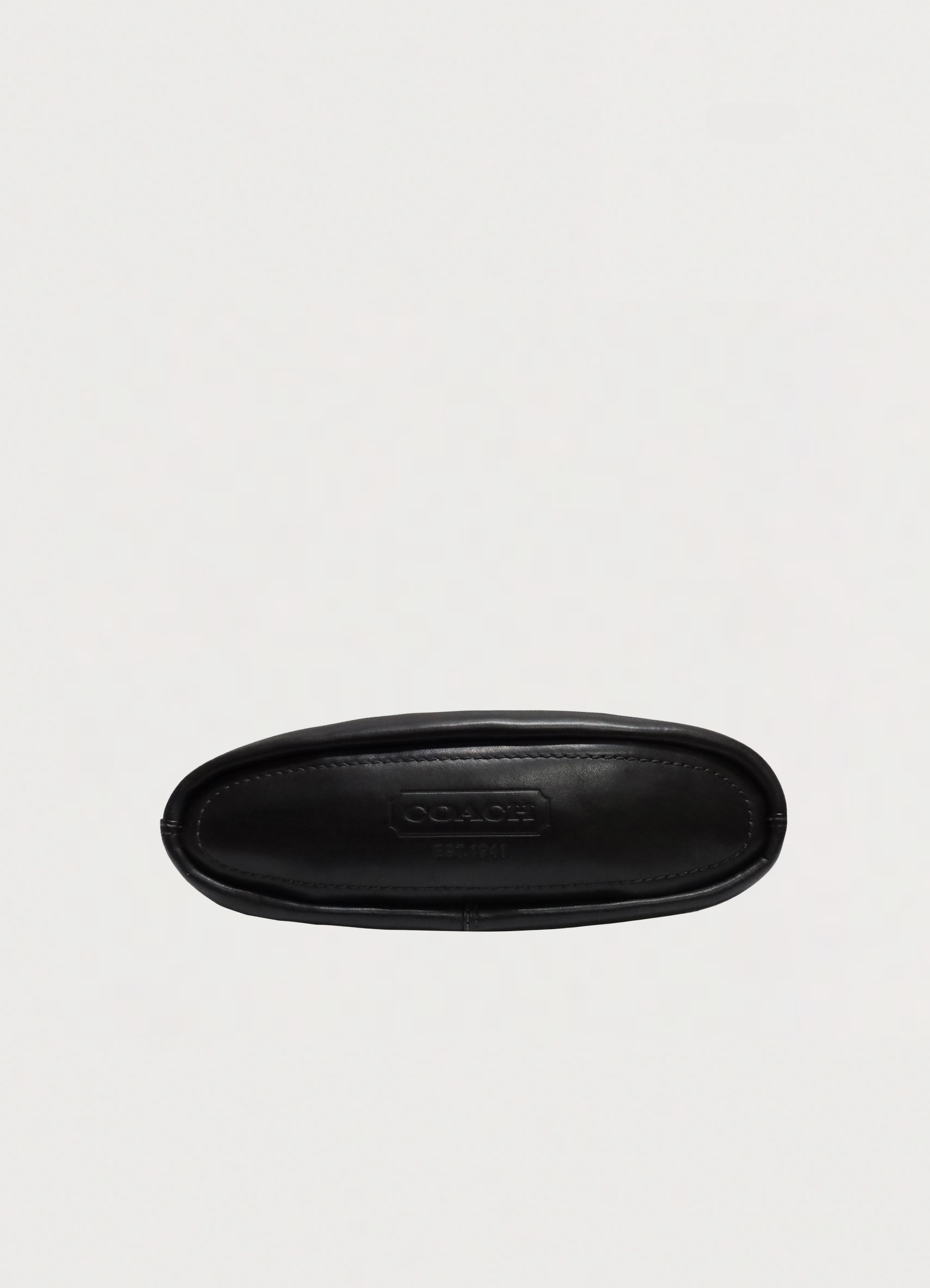 Base view of black Coach Bleecker leather bag showing smooth oval bottom