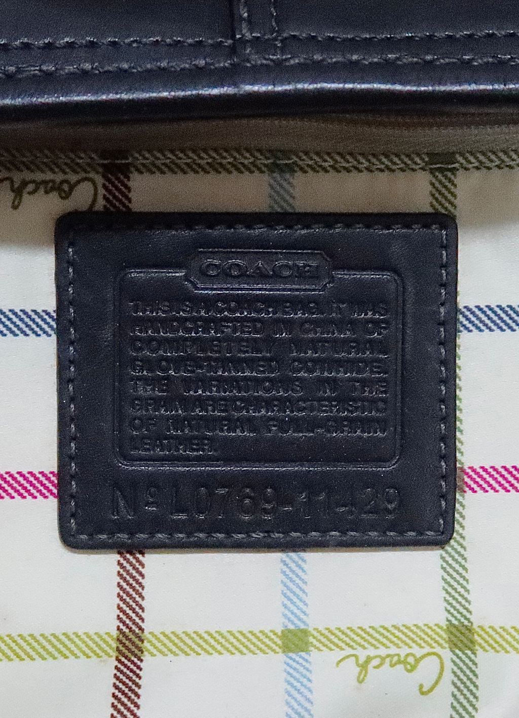 Interior leather Coach creed patch with style number against plaid lining