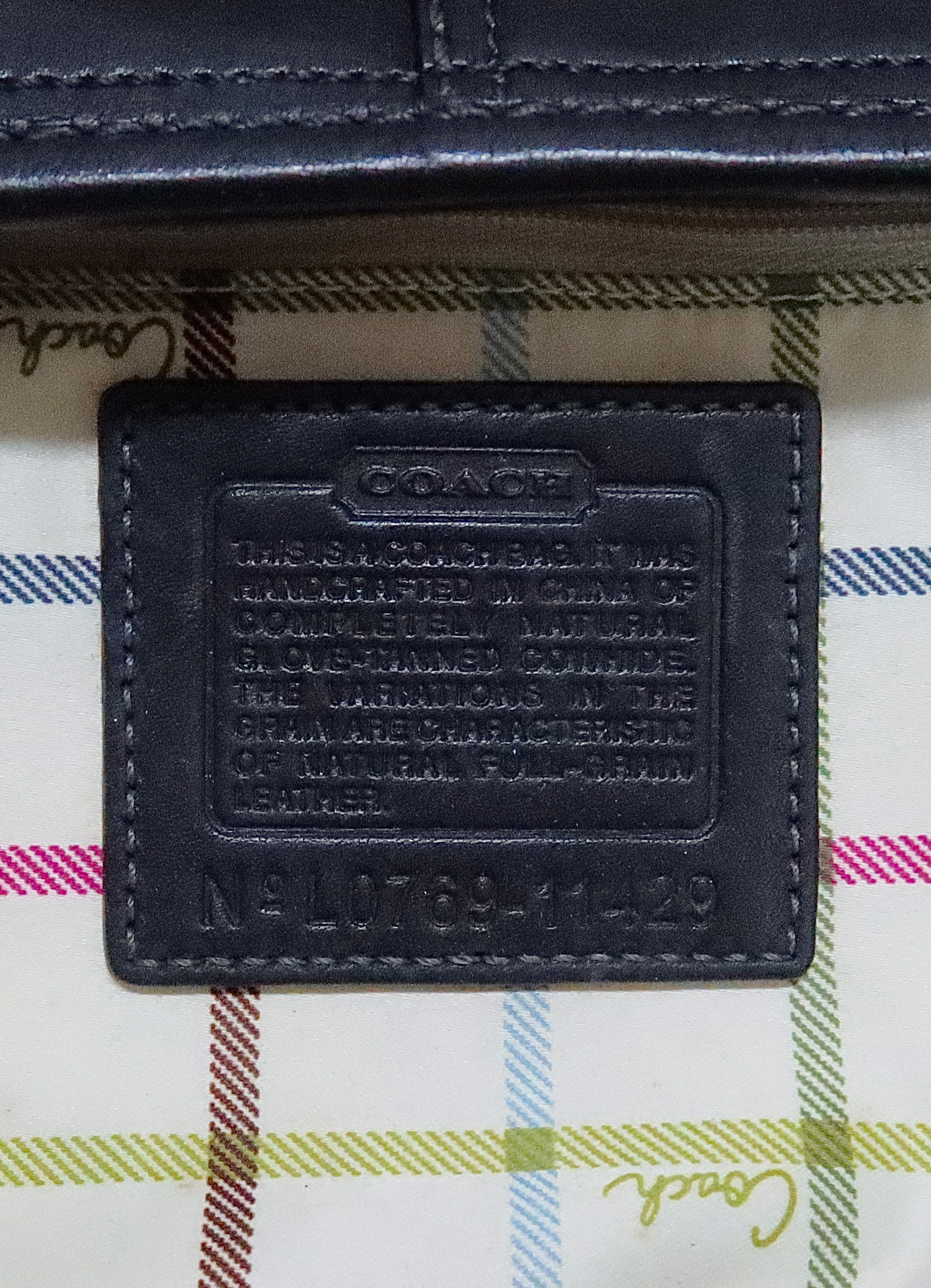 Interior leather Coach creed patch with style number against plaid lining