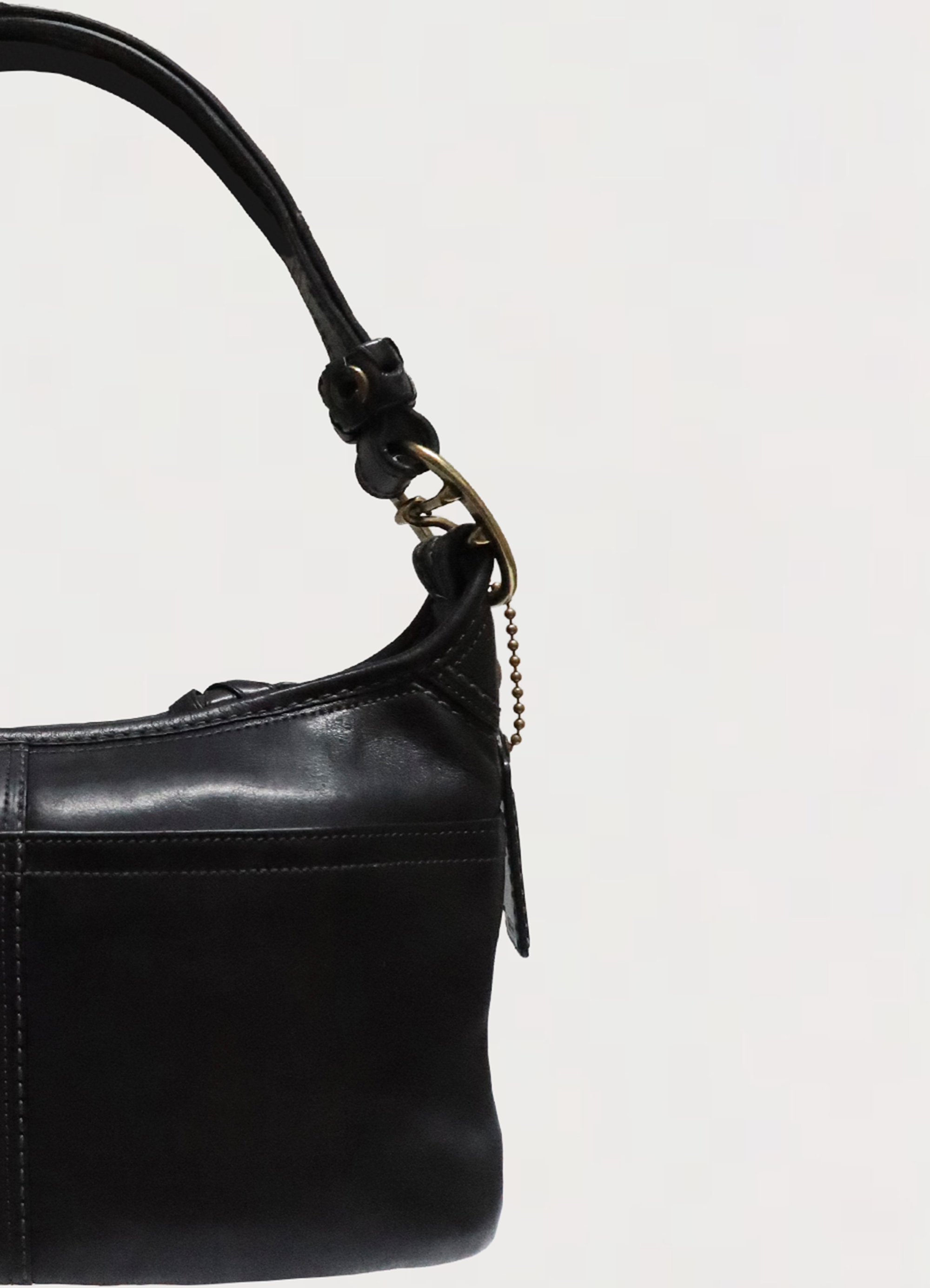 Detail of the black leather shoulder strap with brass buckle hardware