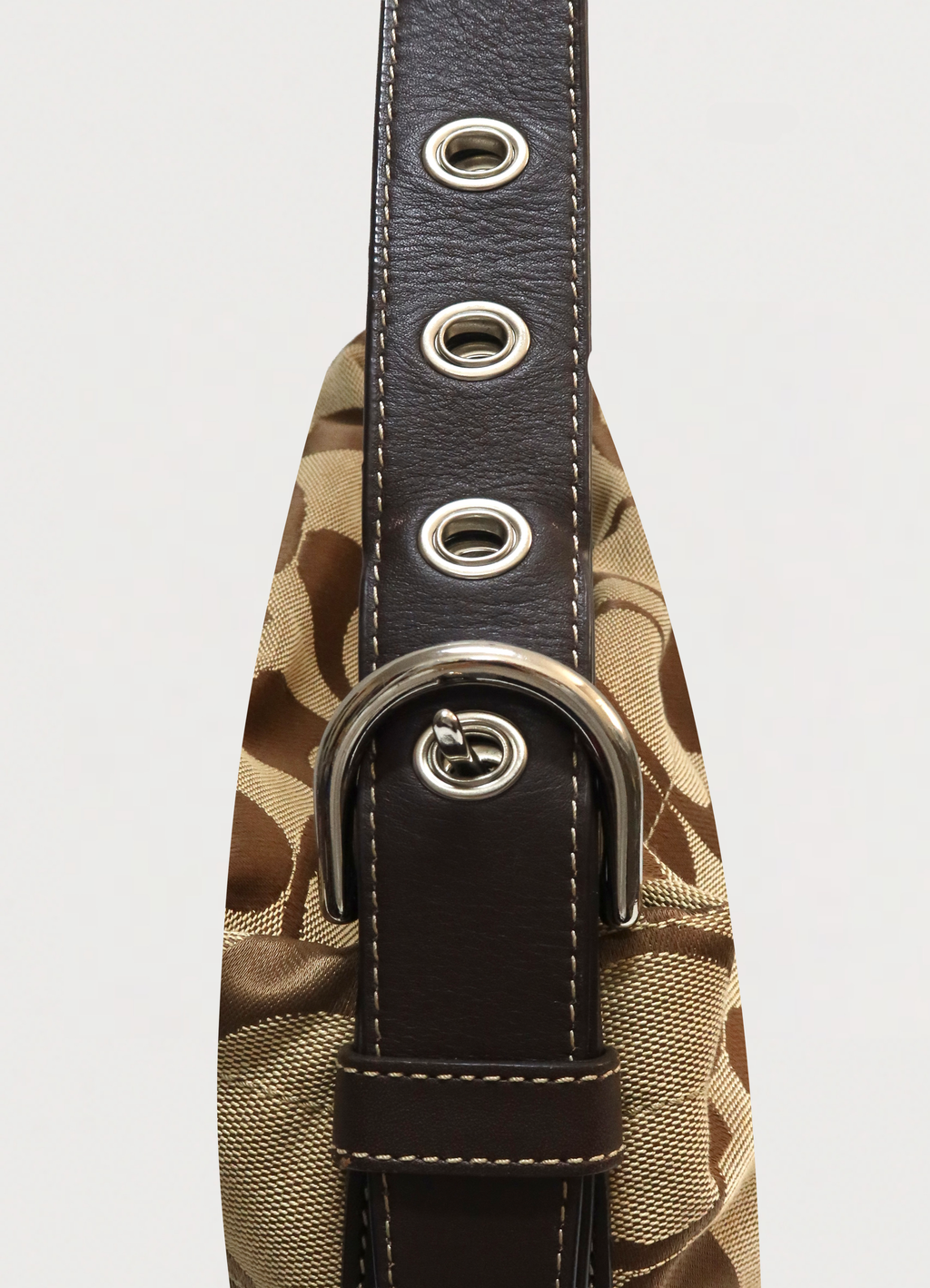 Close up of the silver-tone buckle and grommets on the Coach Bleecker strap