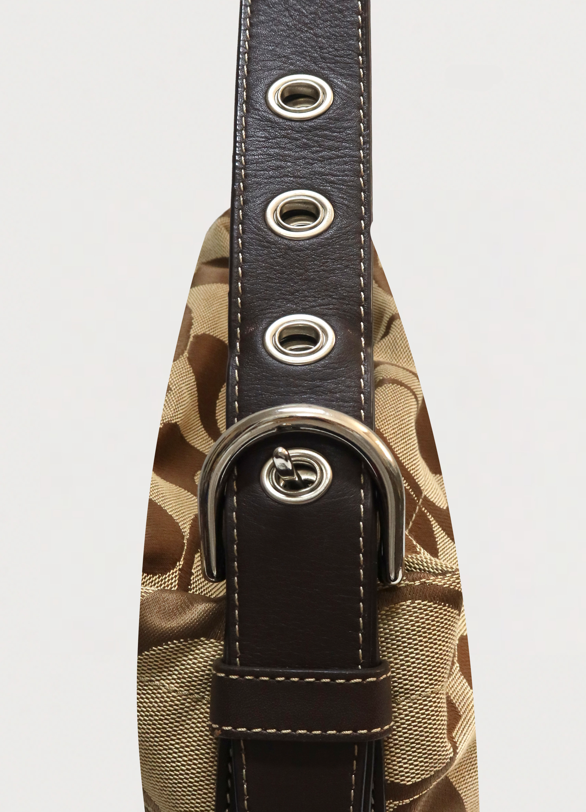 Close up of the silver-tone buckle and grommets on the Coach Bleecker strap