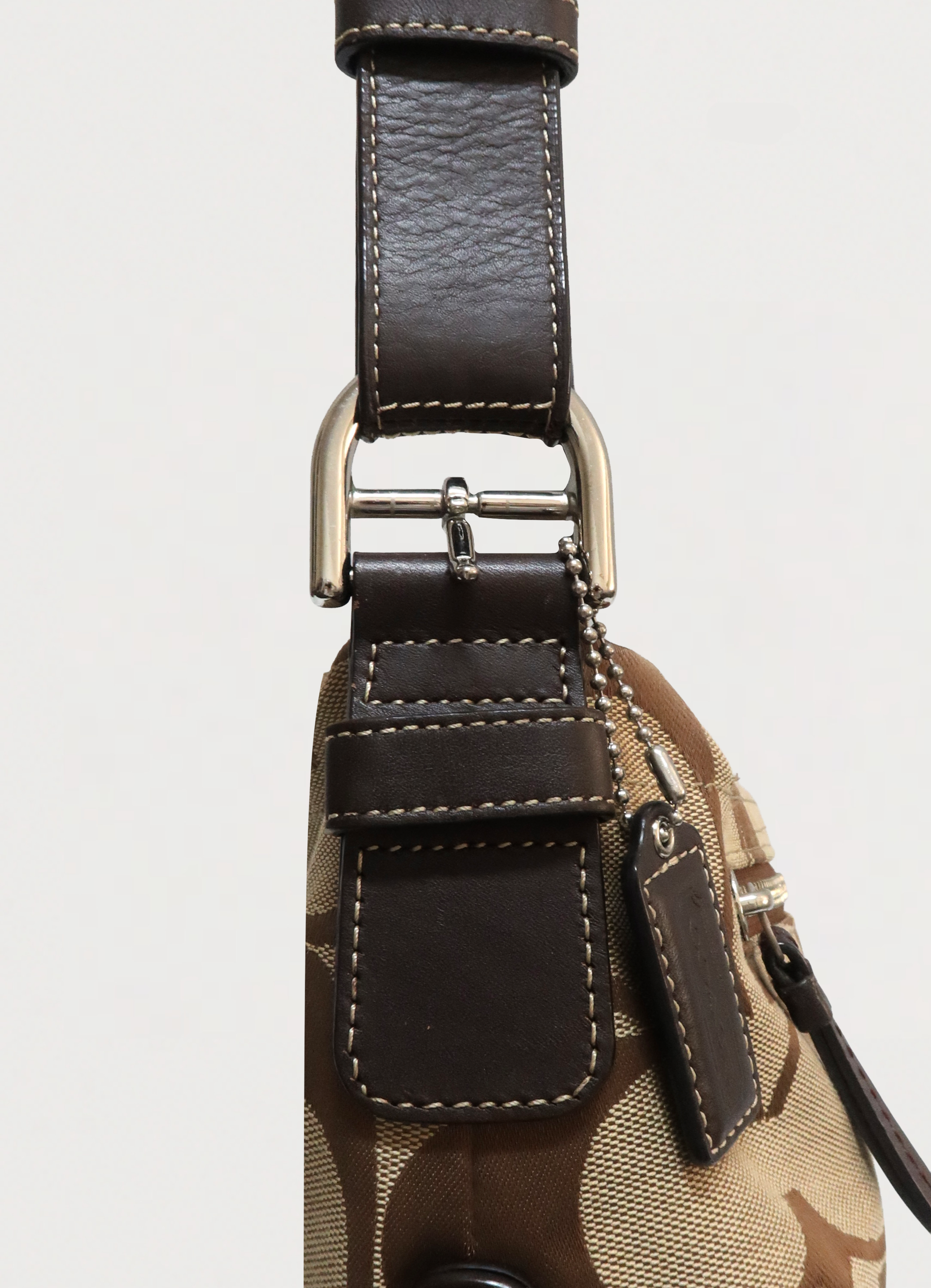 Detailed shot of brown leather buckle strap and stitching on Coach hobo bag