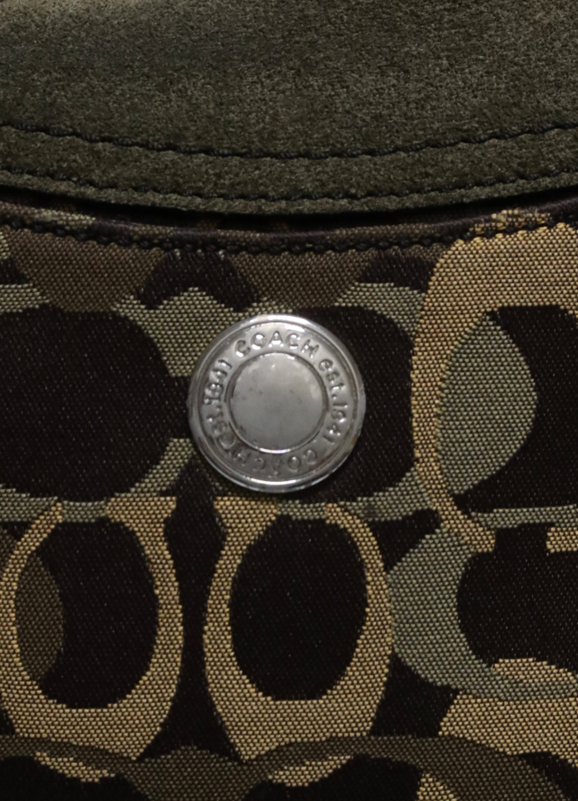 Close up of the silver-tone logo-engraved closure on the Coach Chelsea flap