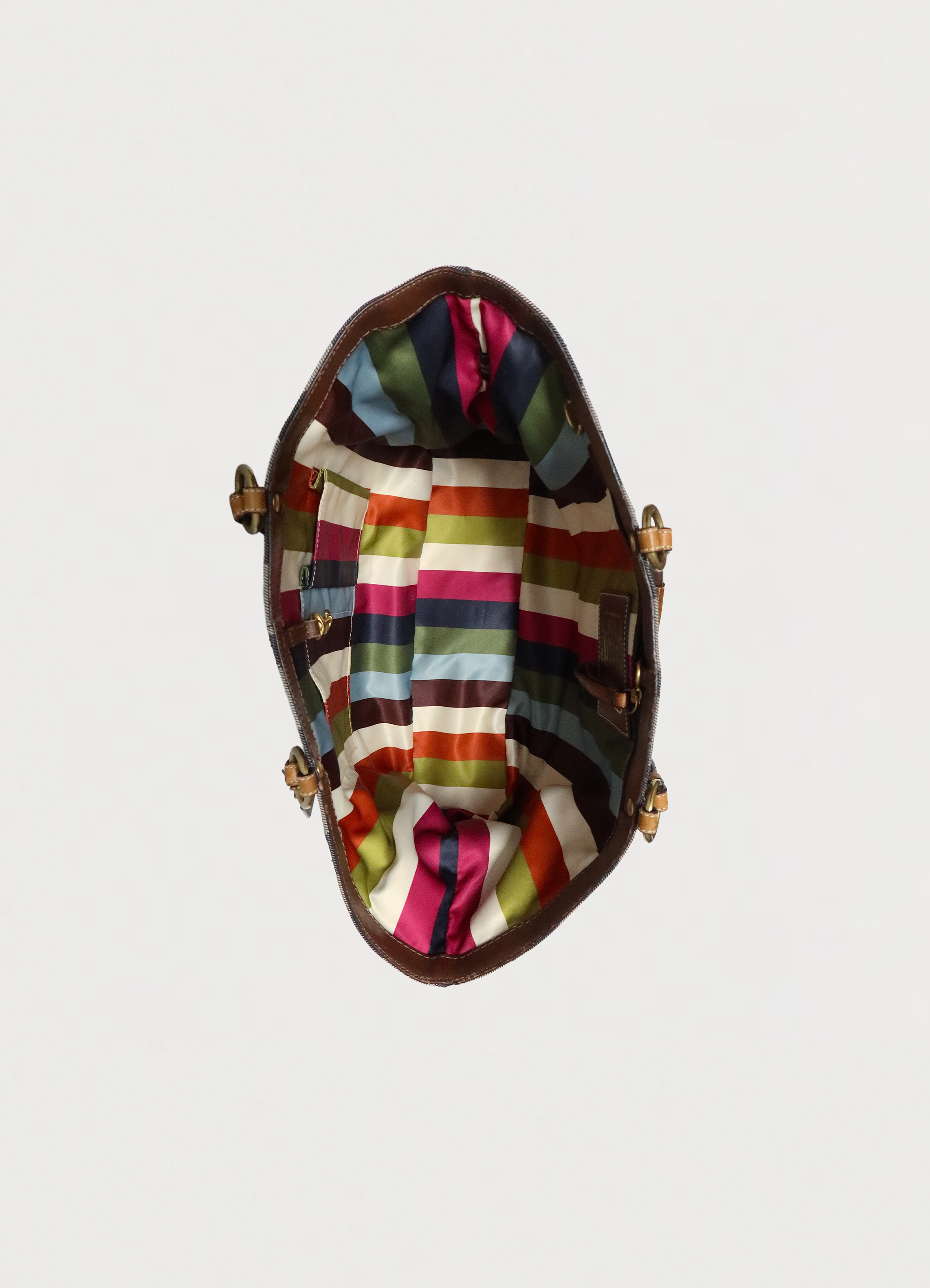Top view of Coach denim tote showing iconic multi-colored striped fabric lining