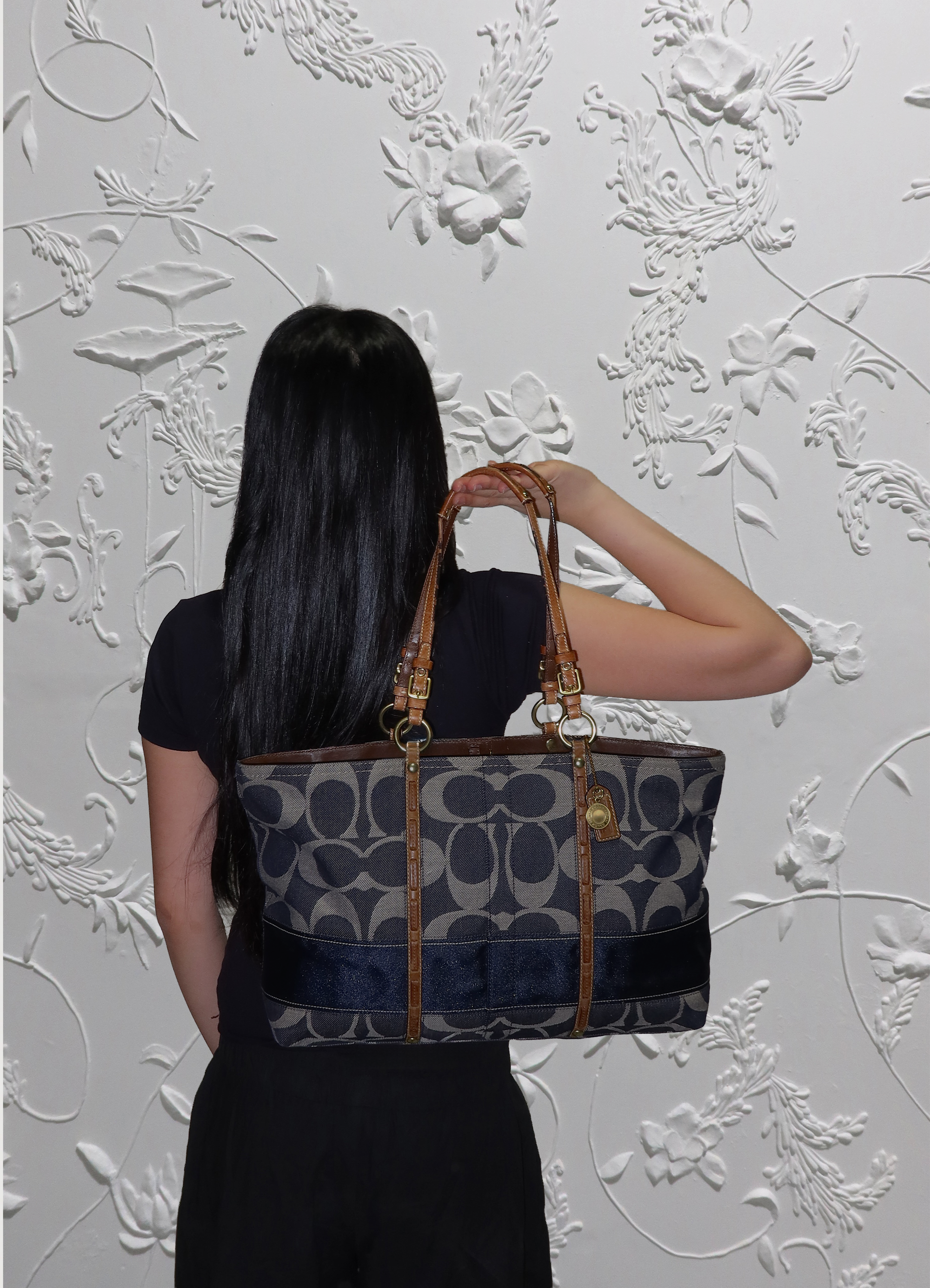 Denim Coach Legacy tote bag held by model 
