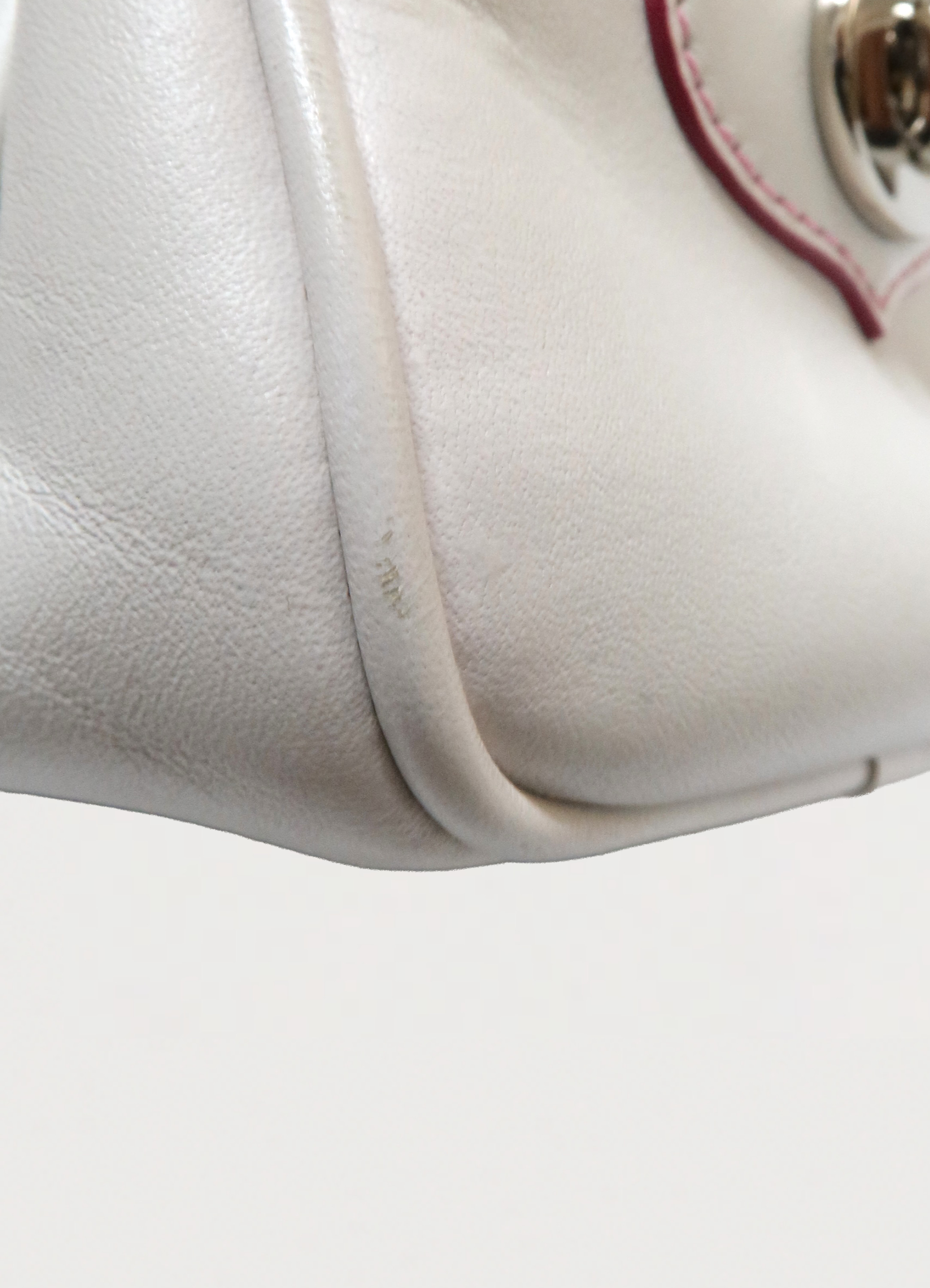 Detailed shot of bottom corner piping and leather texture on the Coach Poppy bag