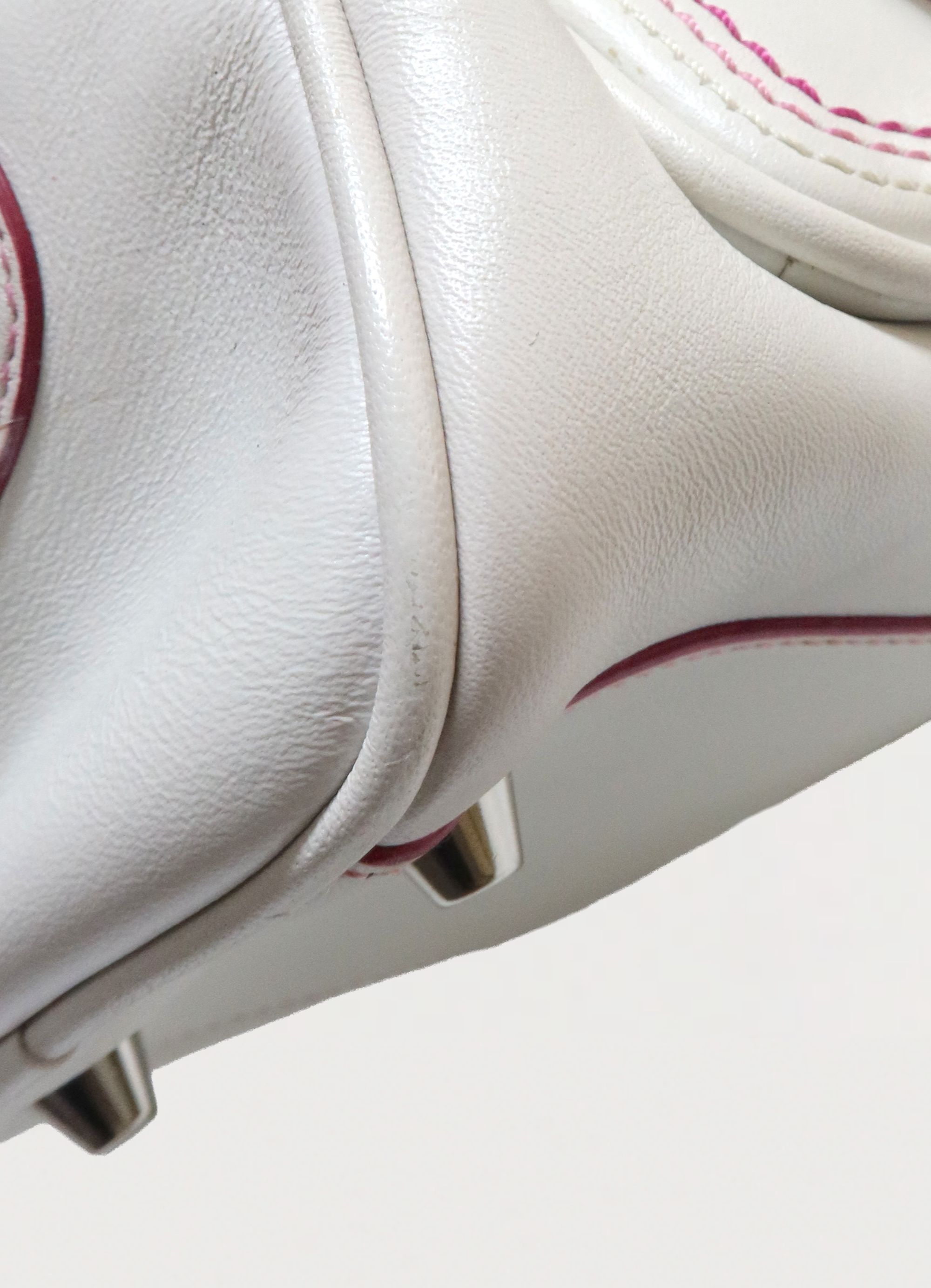 Detailed shot of bottom corner piping and leather texture on the Coach Poppy bag