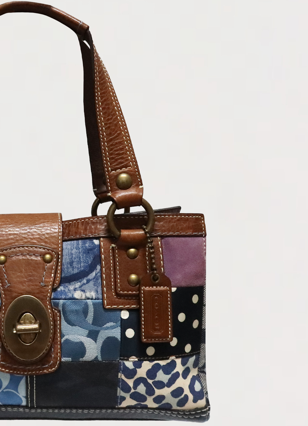 Close up of the tan leather shoulder straps and brass hardware on the Coach satchel