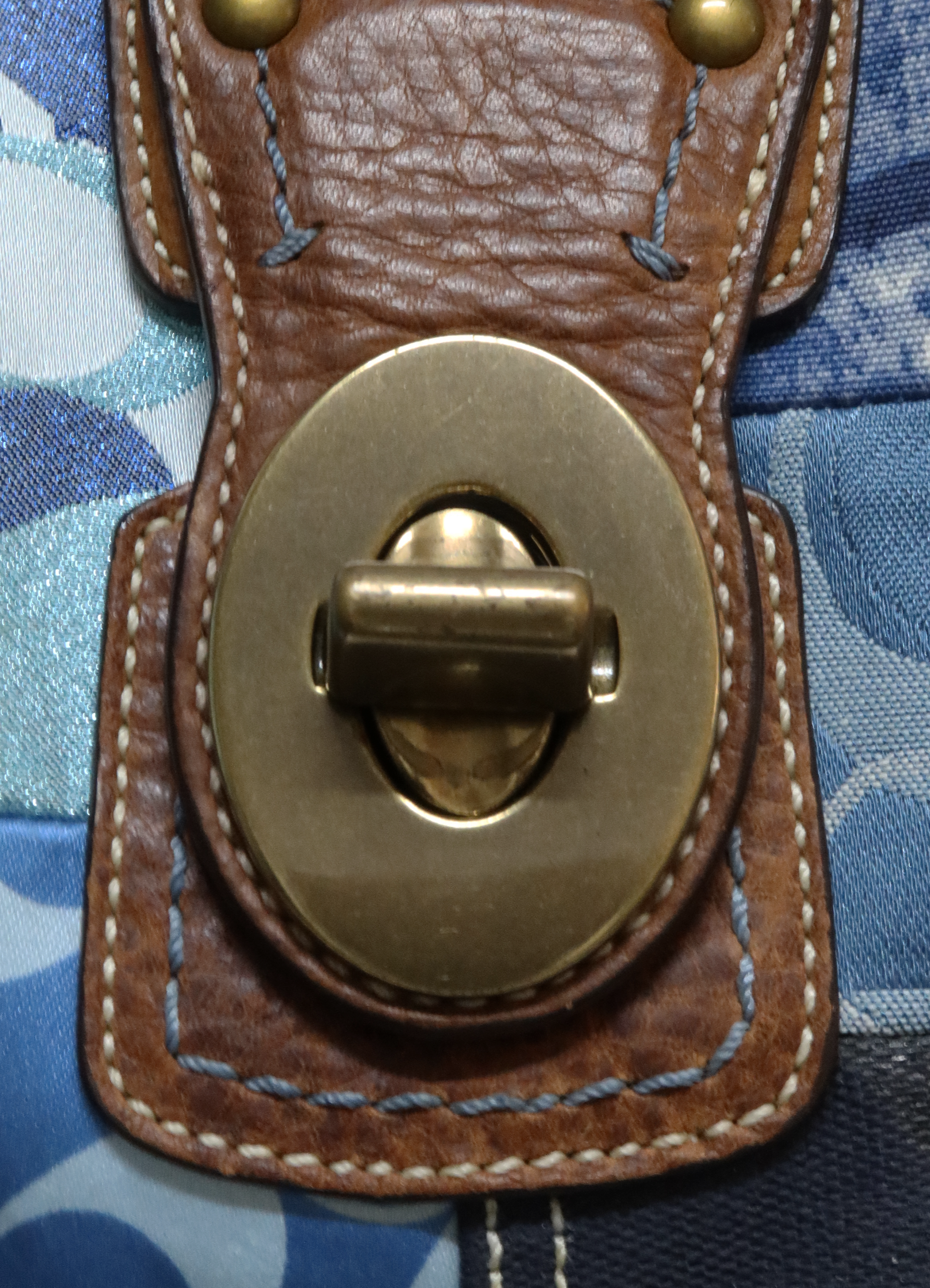 Close up of brass turnlock closure on the front flap of the Coach patchwork bag