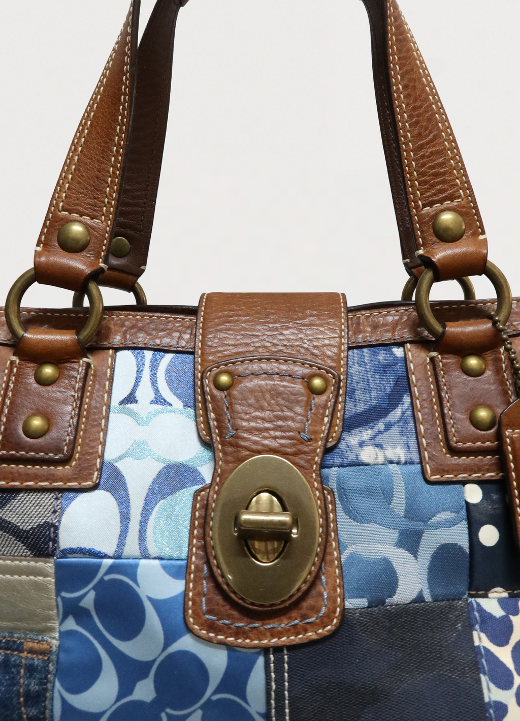 Front view of the brass turnlock and tan leather trim on Coach satchel