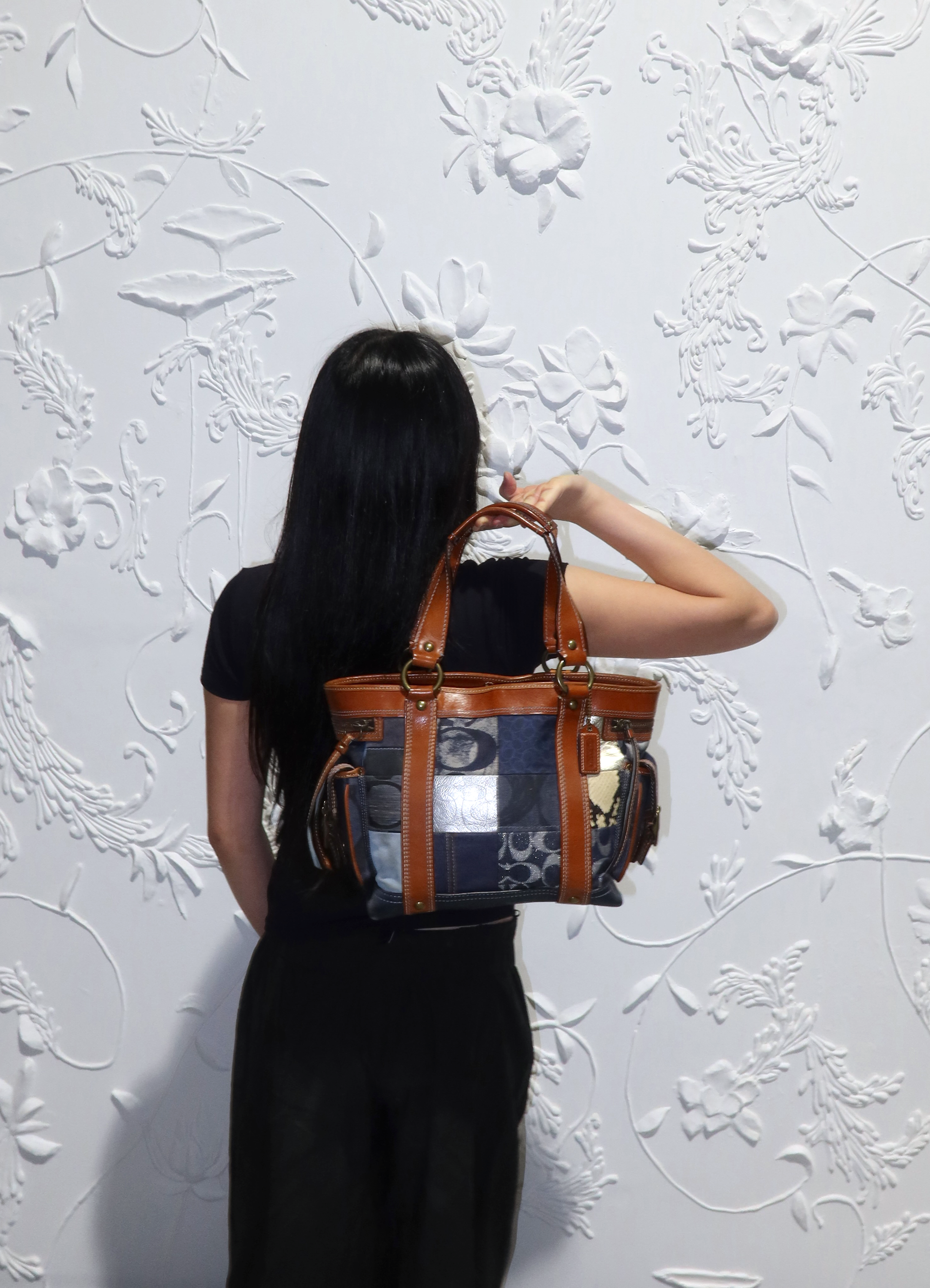 Coach Legacy denim patchwork tote bag held by model