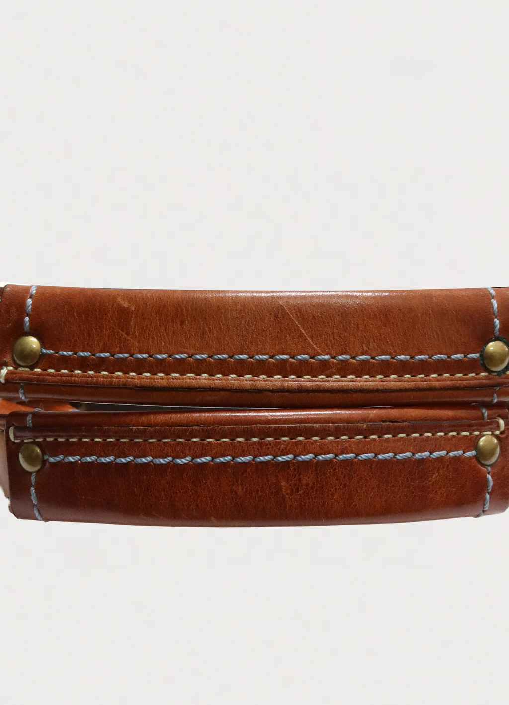 Close up of the brass O-ring and tan leather handle attachment on Coach denim bag