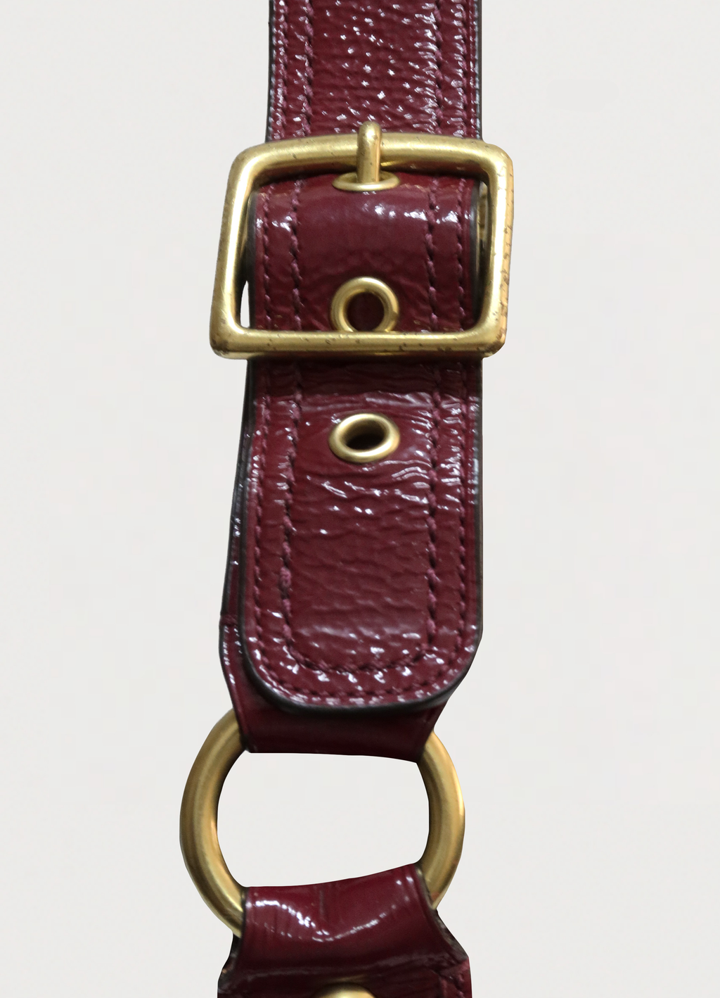 Detail of the brass buckle and beet red leather strap on Coach pouch