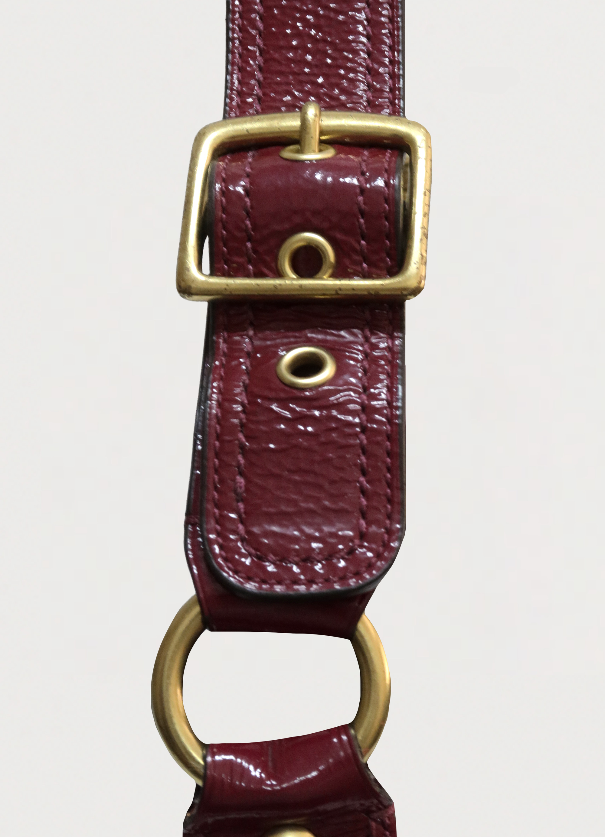 Detail of the brass buckle and beet red leather strap on Coach pouch