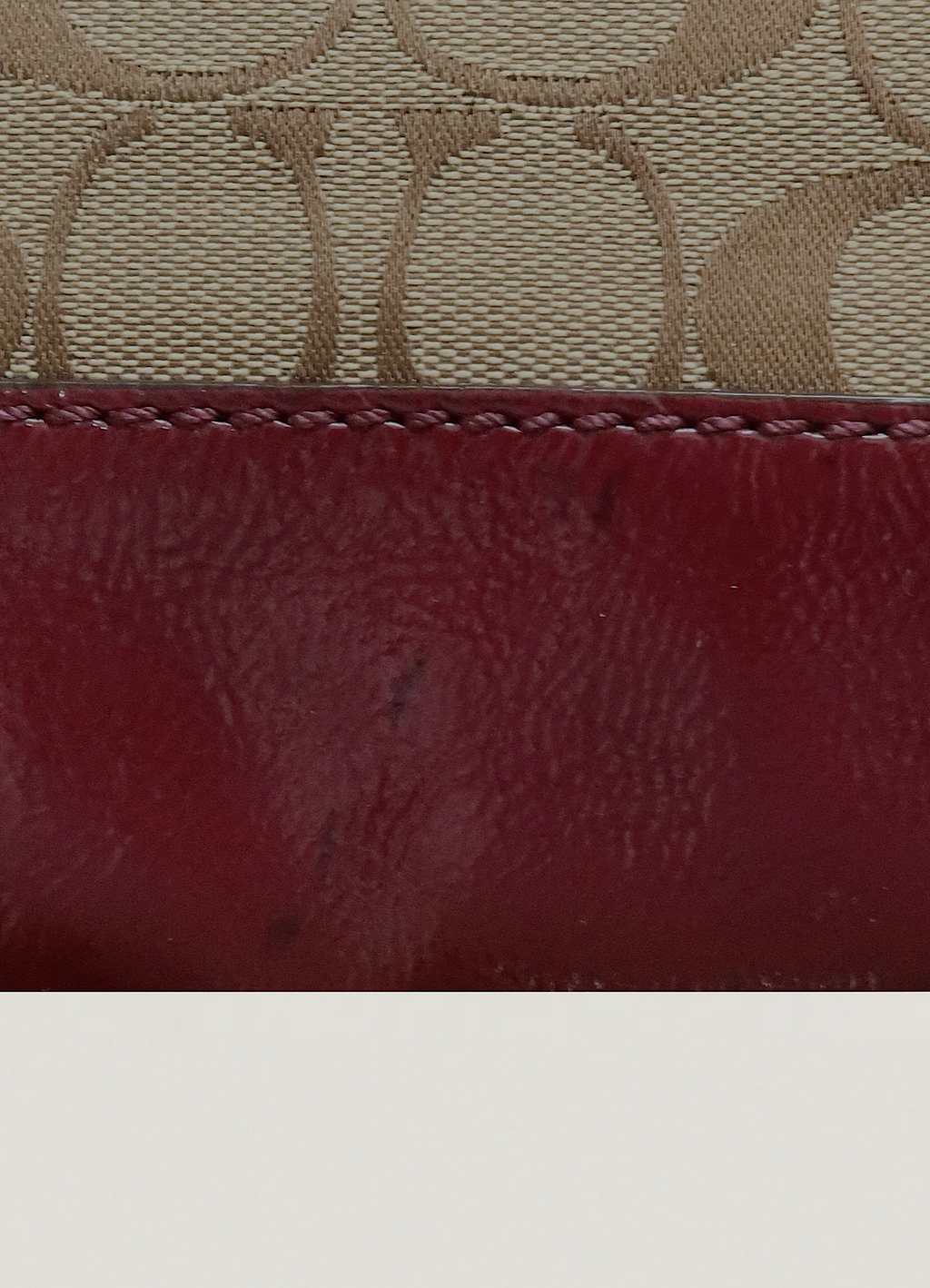 Detail of the beet red leather trim finish on Coach signature canvas