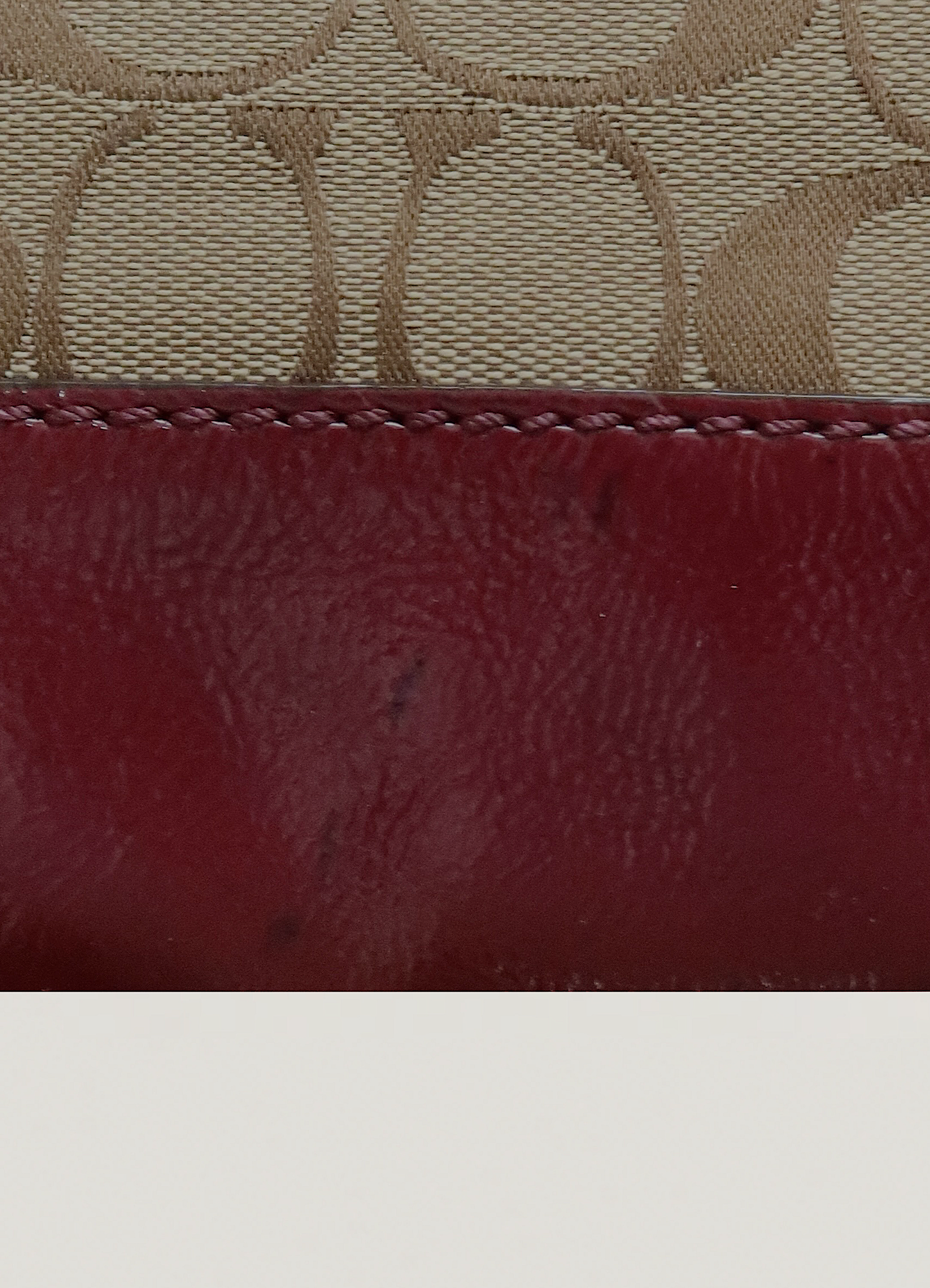 Detail of the beet red leather trim finish on Coach signature canvas