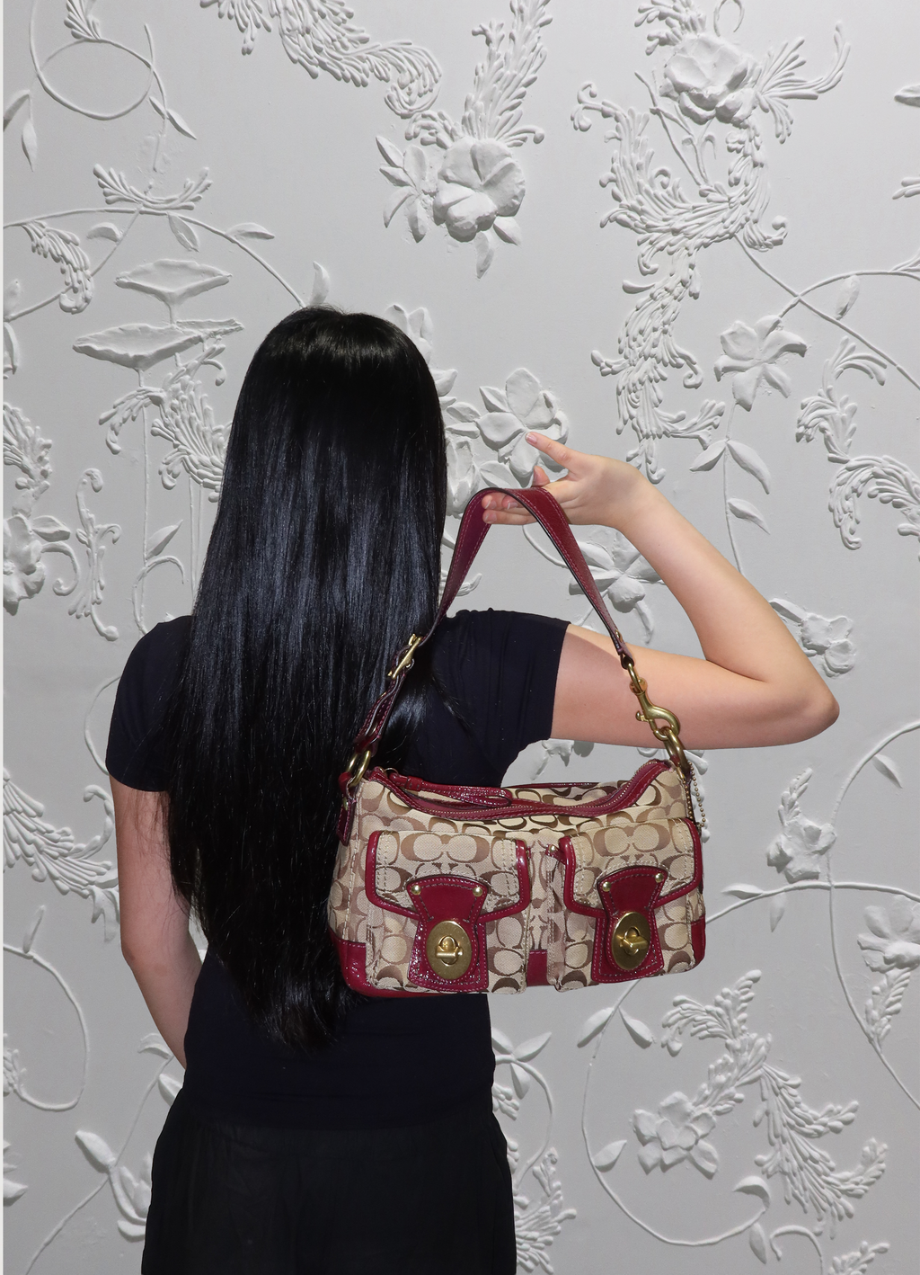 Coach Legacy turnlock pouch bag held by model