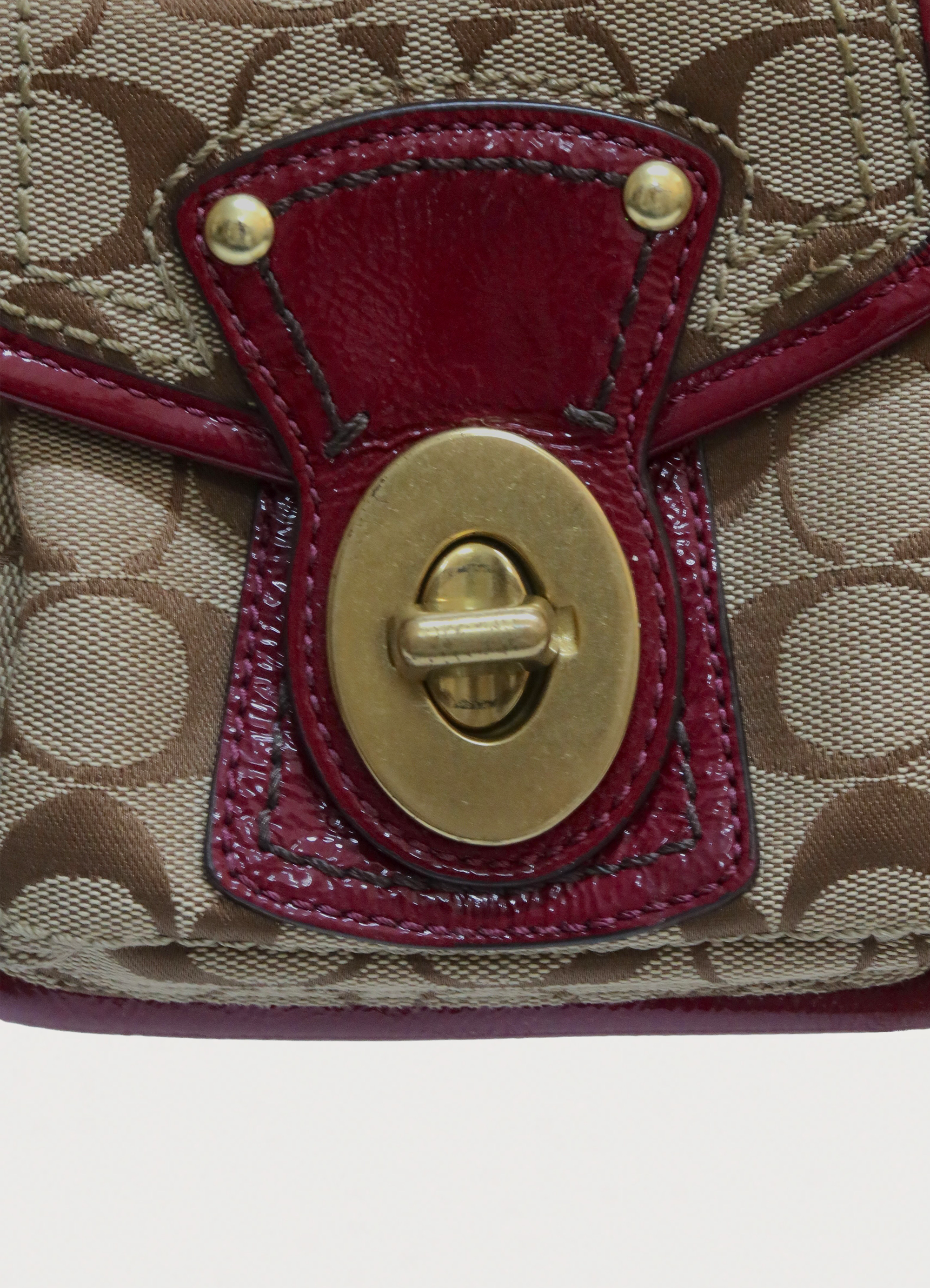 Close up of brass turnlock hardware on the front pocket of Coach Legacy bag