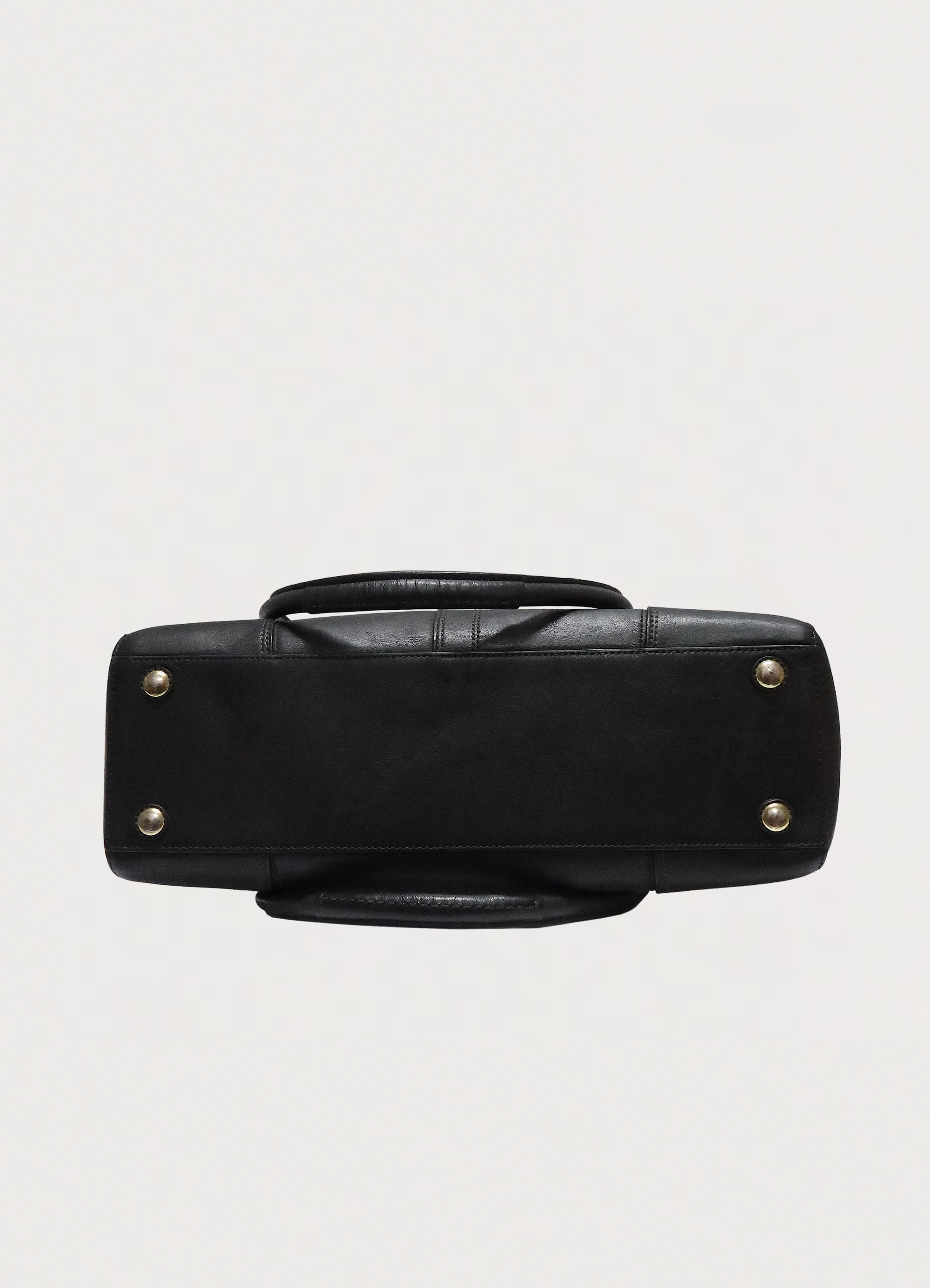 Base view of Coach Madeline black leather satchel showing brass metal feet