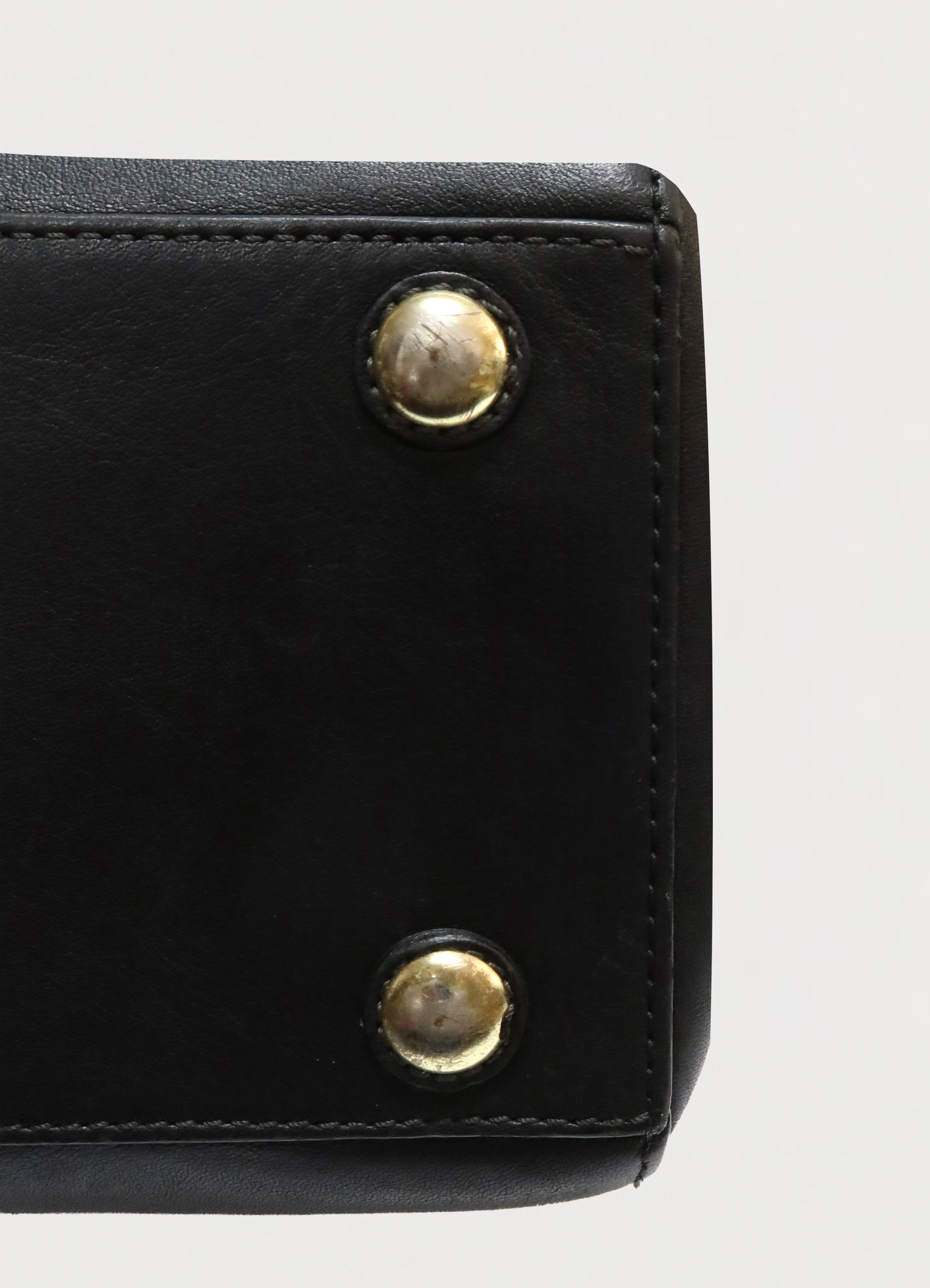 Corner view of the base of the Coach Madeline bag showing leather condition and brass feet
