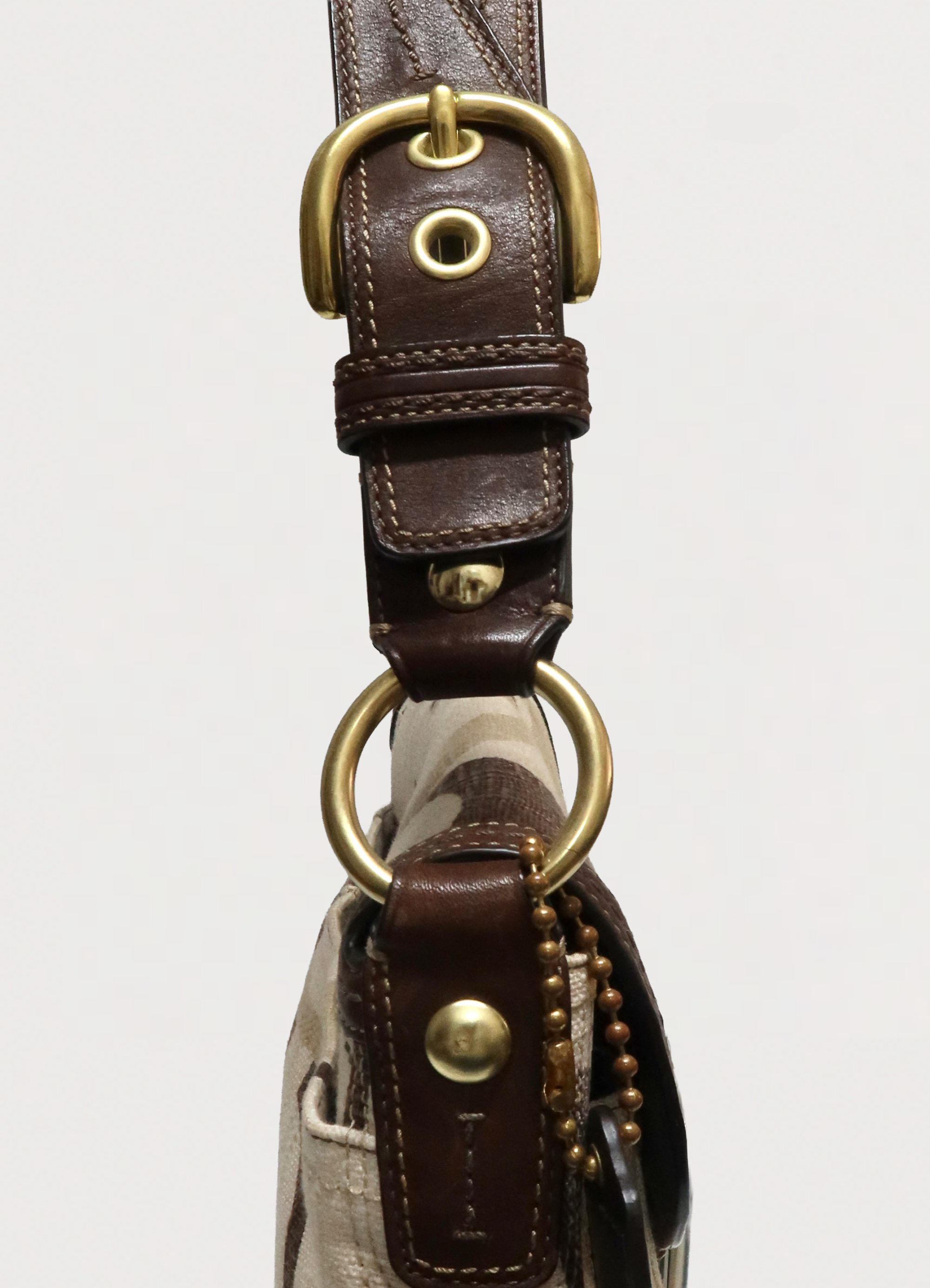 Close up of brass O-ring and adjustable leather strap on Coach Soho bag