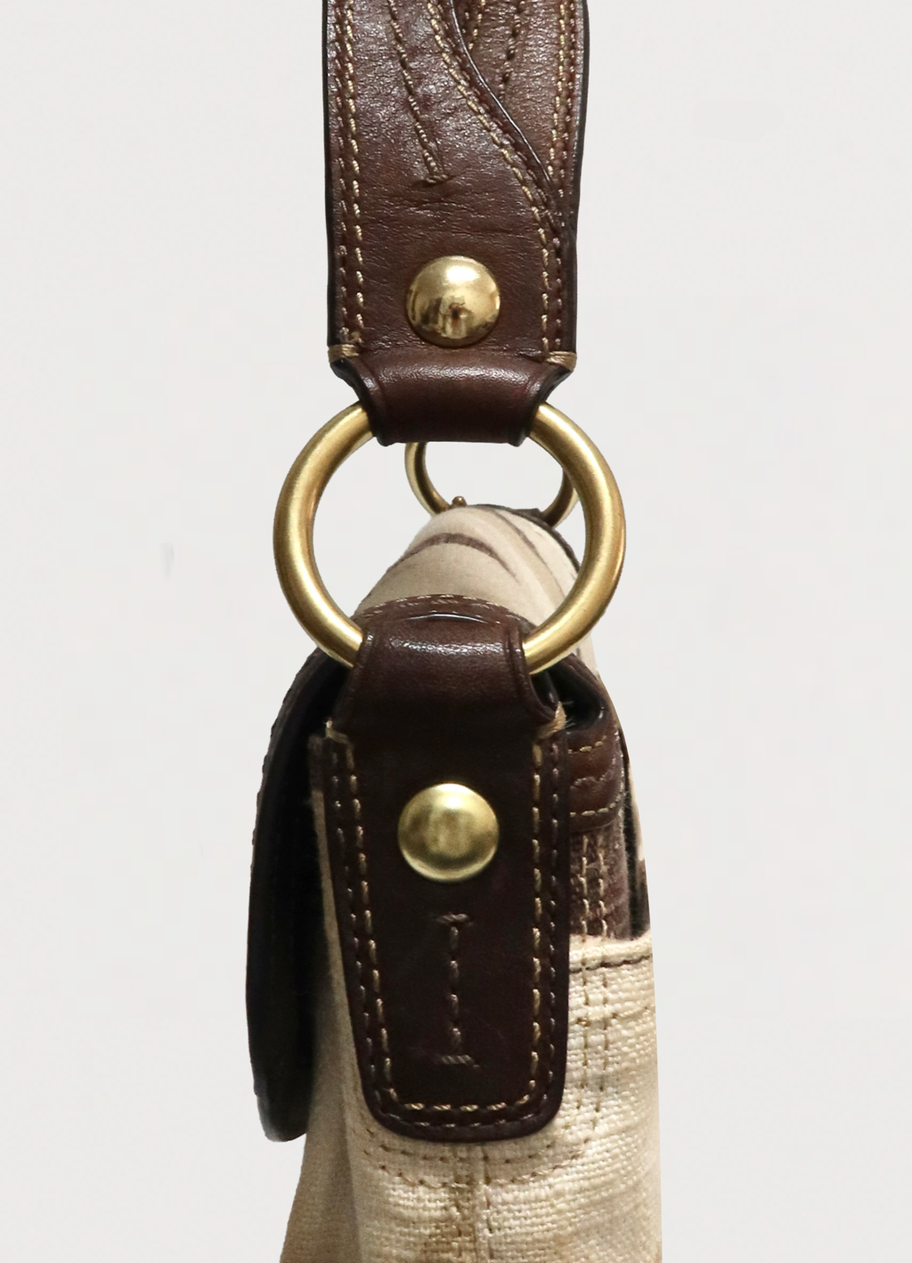 Detail of brass rivets and leather strap attachment on Coach Soho shoulder bag