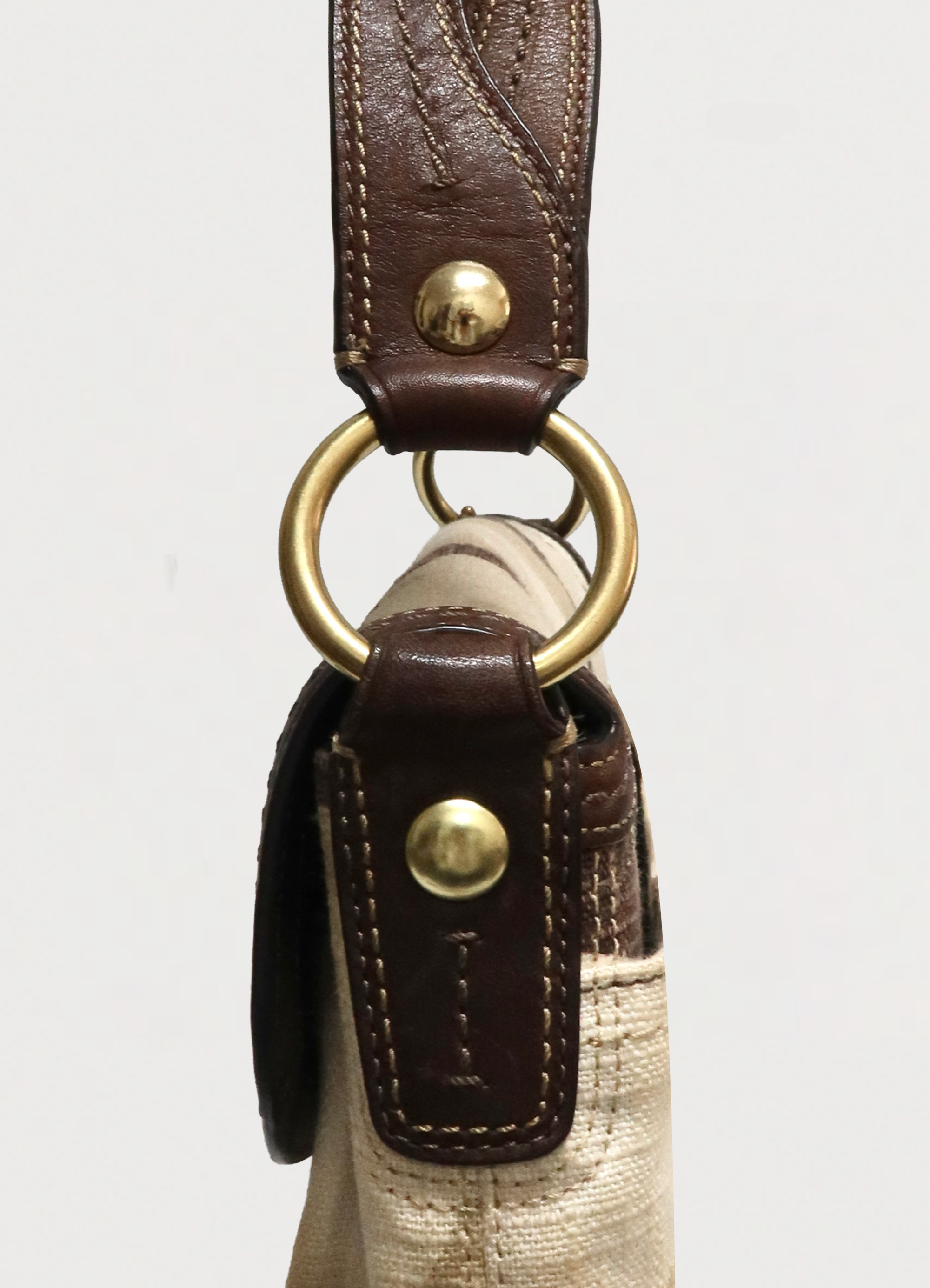 Detail of brass rivets and leather strap attachment on Coach Soho shoulder bag