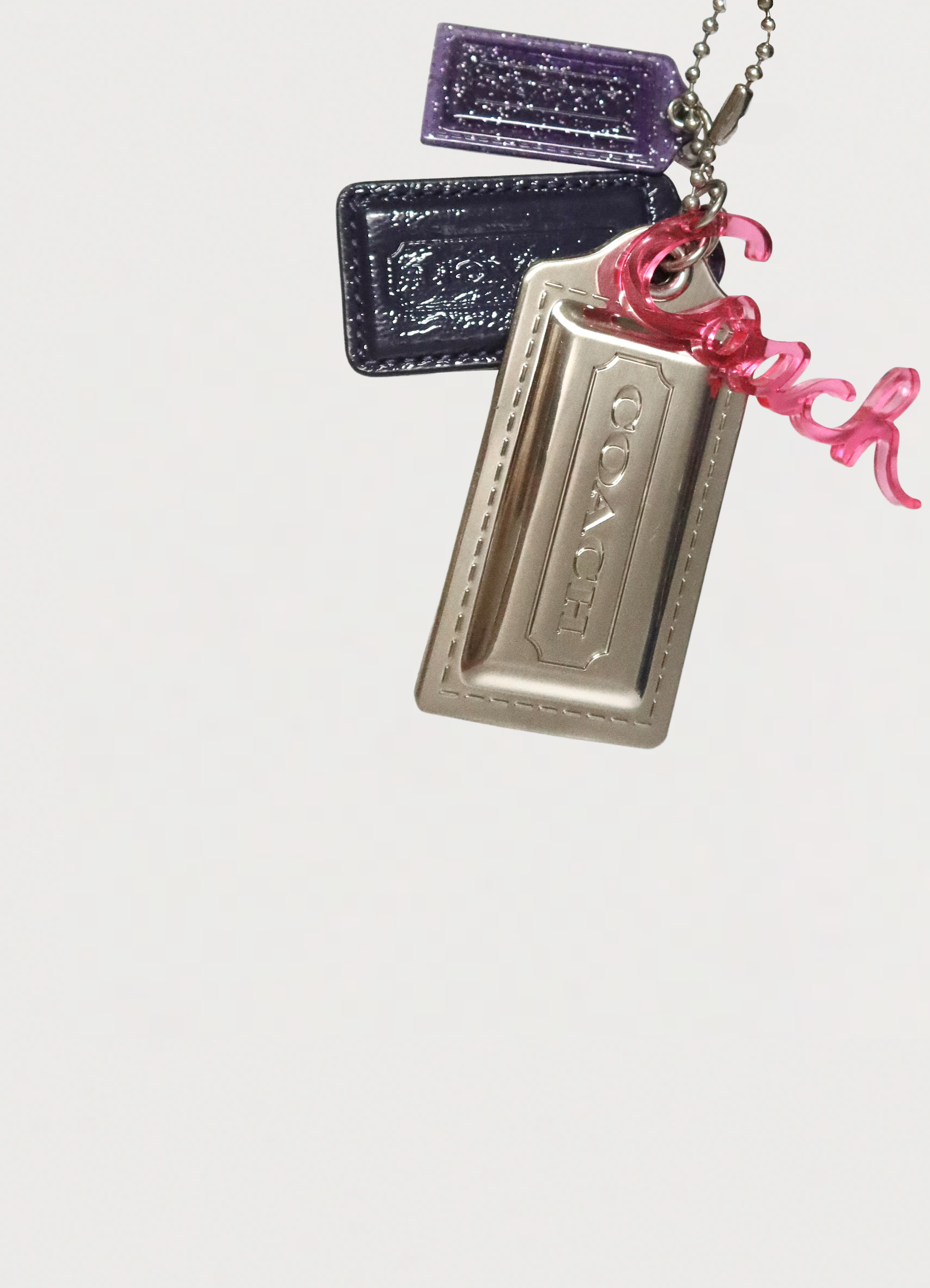 Close up of Coach Poppy signature hangtags including silver, purple, and pink logos