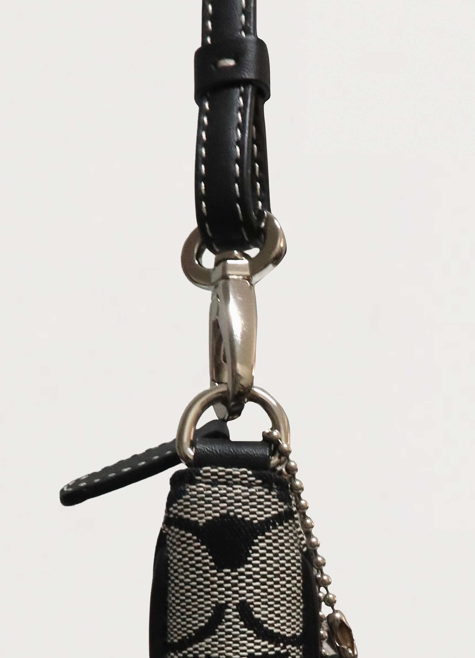 Detail shot of the silver-tone zipper pull and leather trim on the Coach demi bag