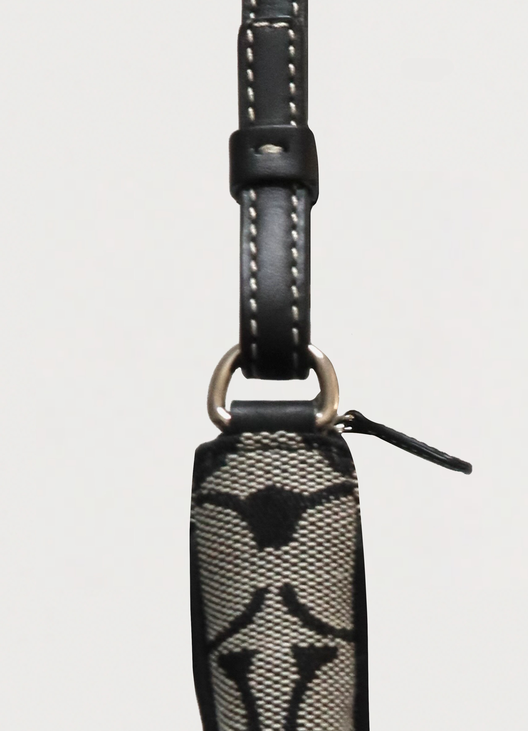 Detail shot of the silver-tone zipper pull and leather trim on the Coach demi bag