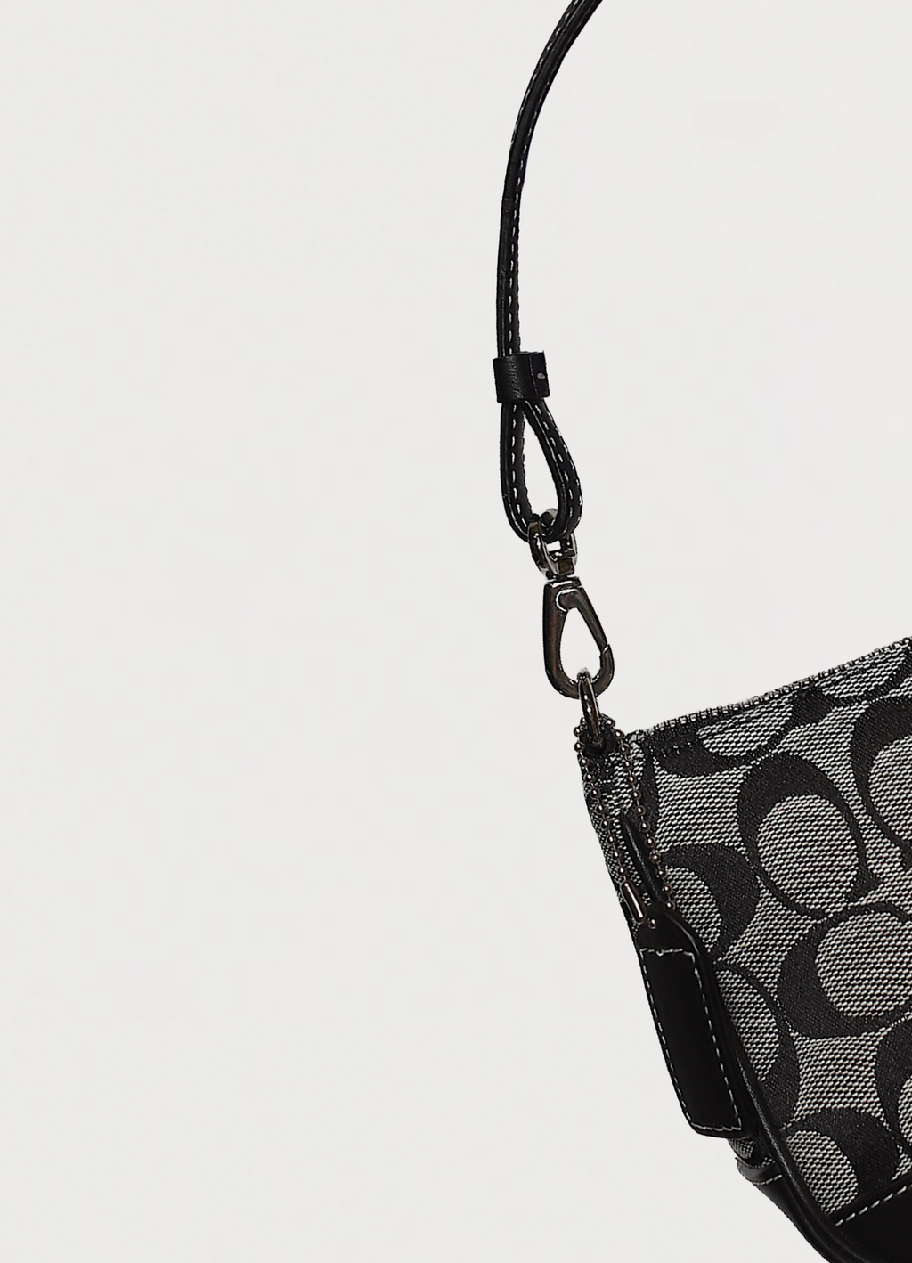 Close up of the silver-tone dog-leash clip and leather strap on Coach pochette