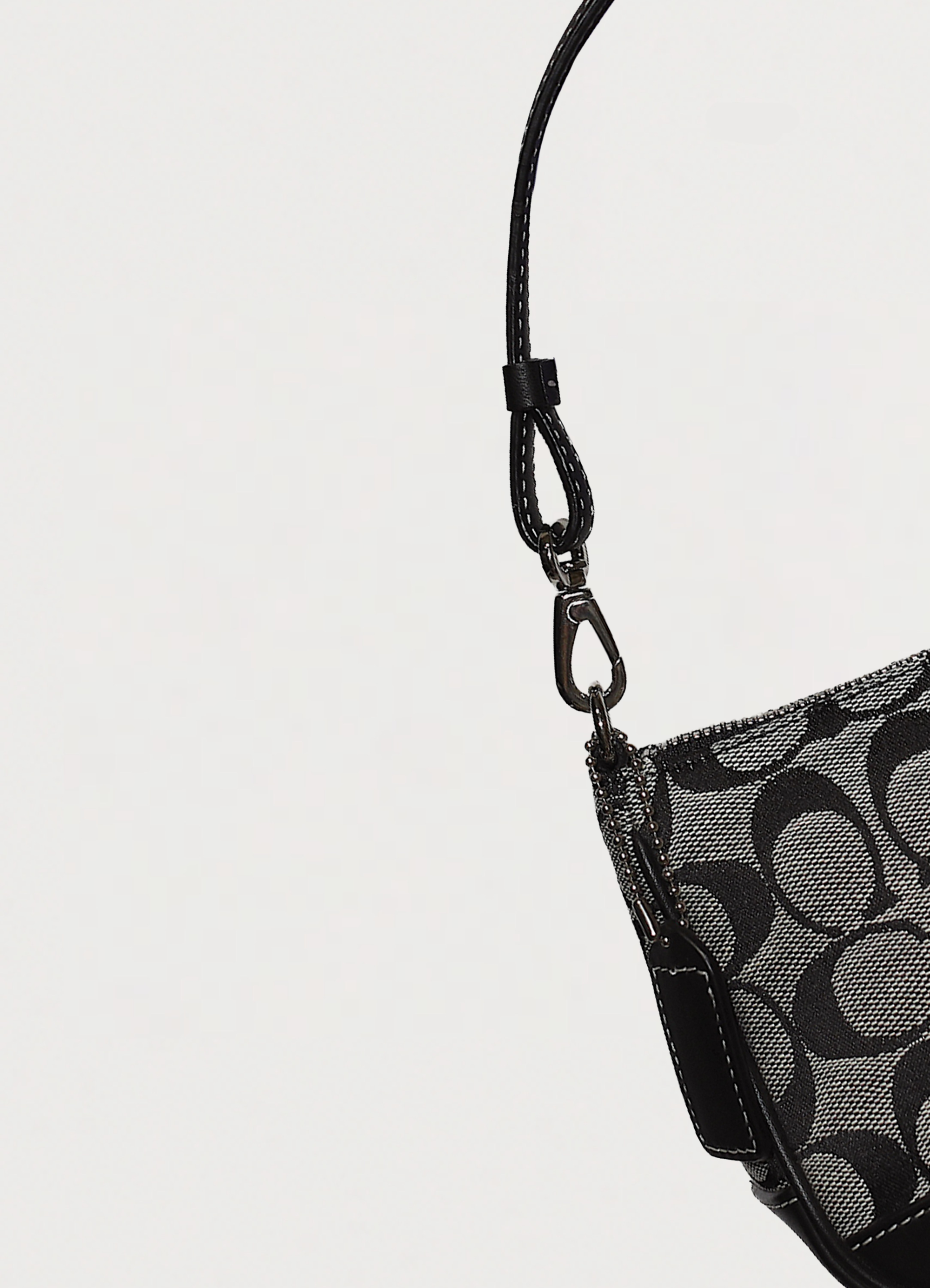 Close up of the silver-tone dog-leash clip and leather strap on Coach pochette